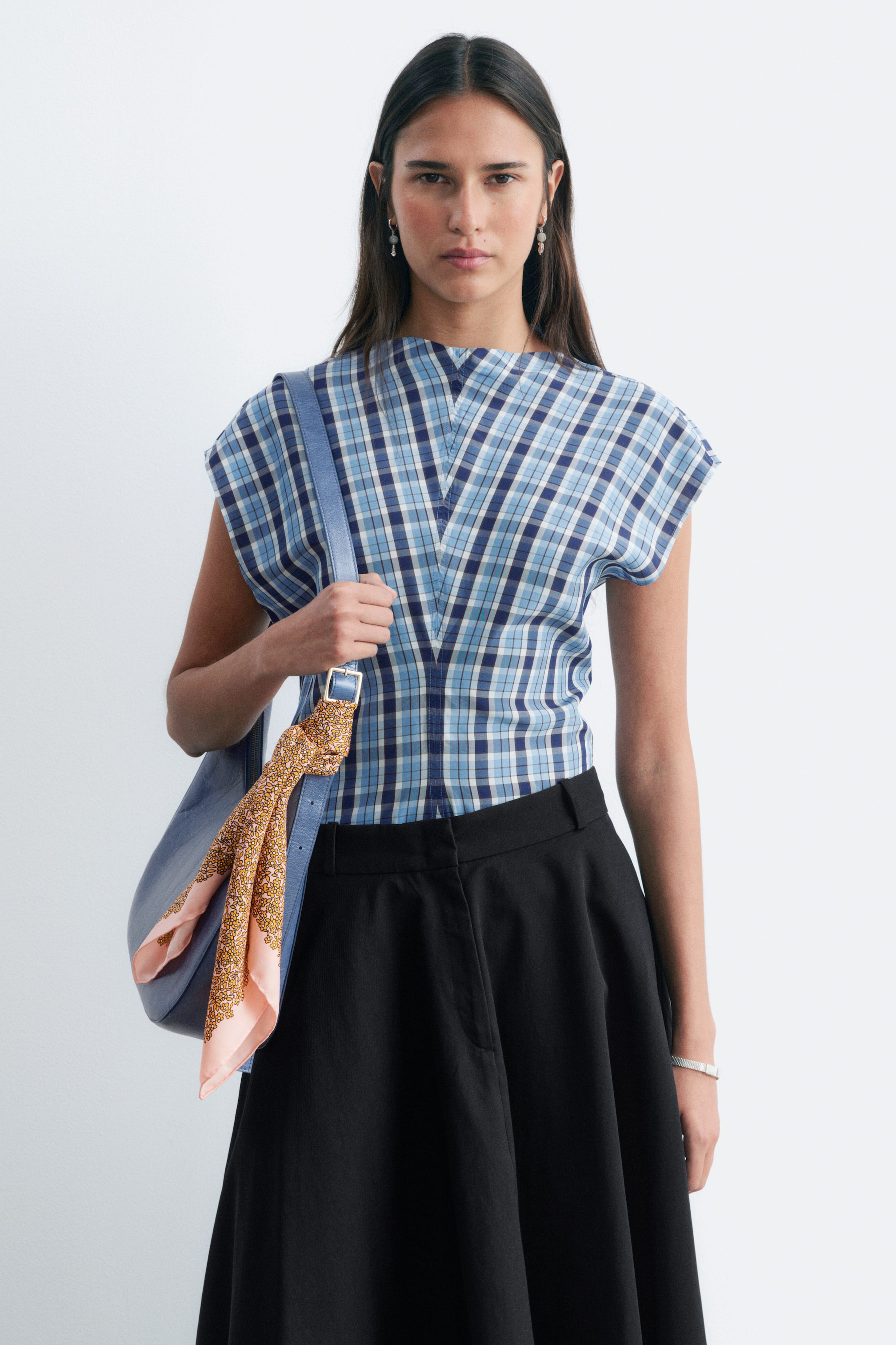 View larger image: The black skirt features a flared A-line silhouette with a flat waistband and falls to a midi length. It is shown from a front-left angle.