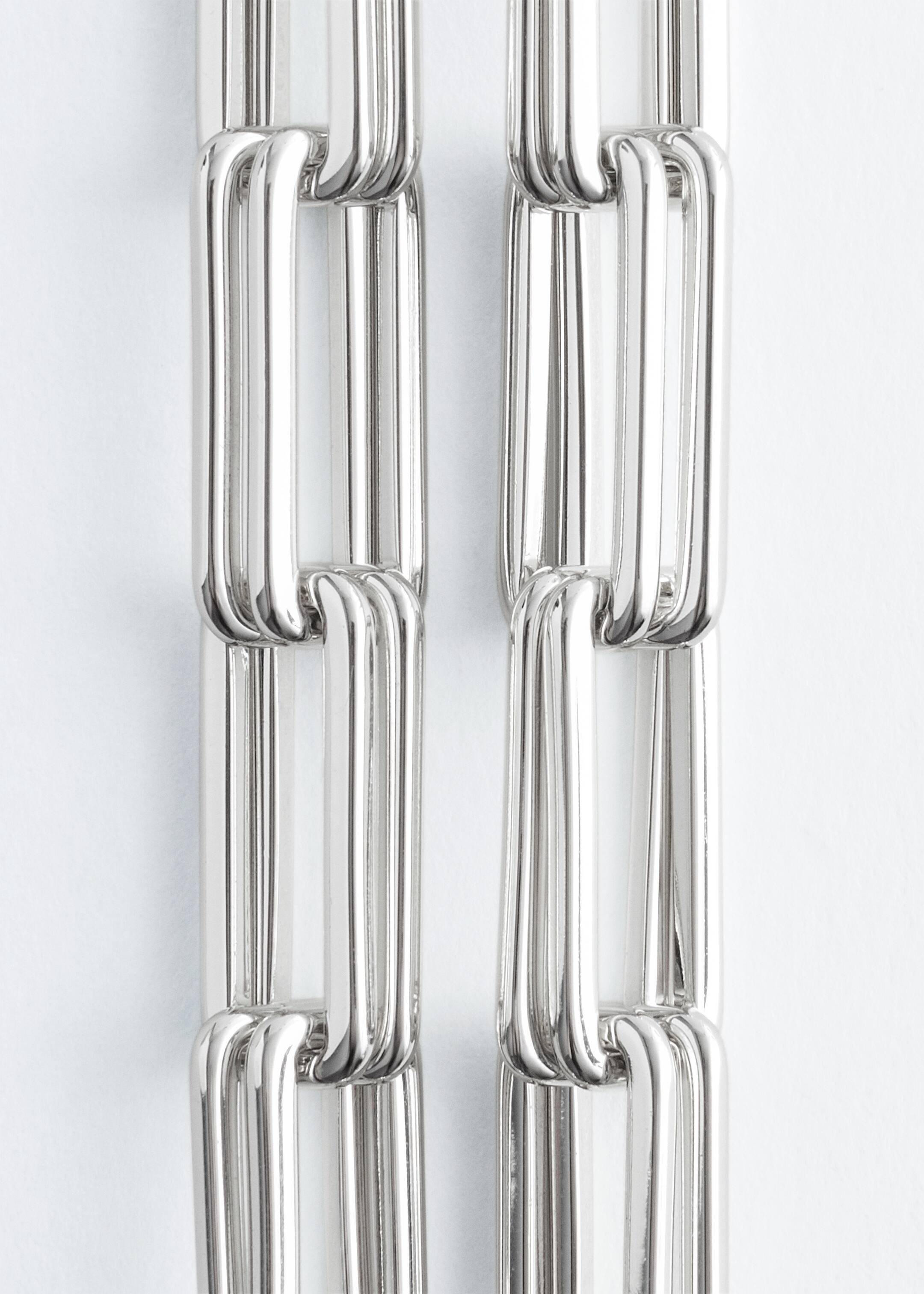 Agrandir l'image: Un collier à maillons épais est présenté, avec des maillons rectangulaires allongés et épais aux coins arrondis. Les maillons sont polis et semblent tubulaires, affichant une finition métallique argentée et brillante.