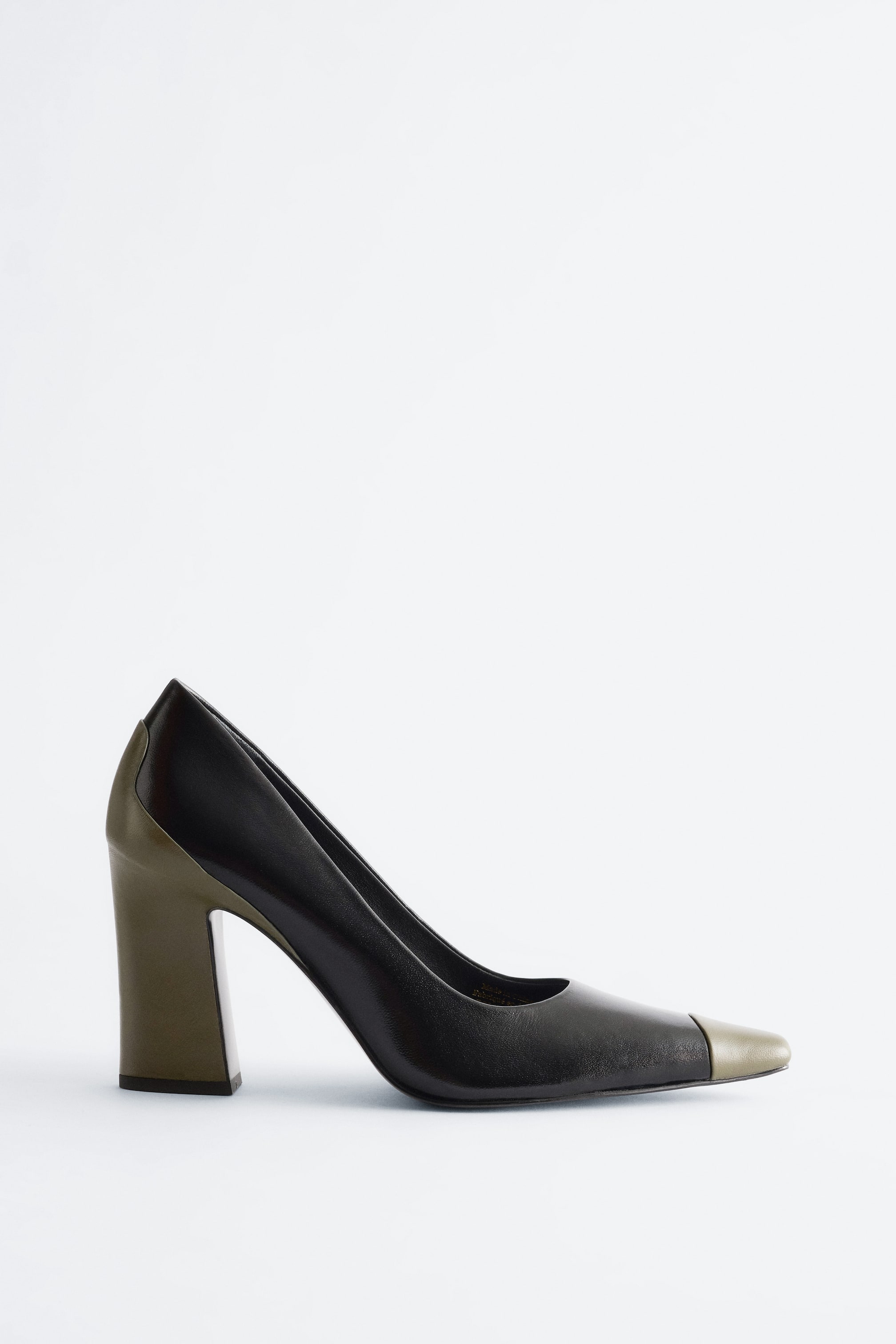 View larger image: A leather court shoe is facing left, showcasing a black main body with a contrasting olive green pointed toe cap and a chunky block heel.