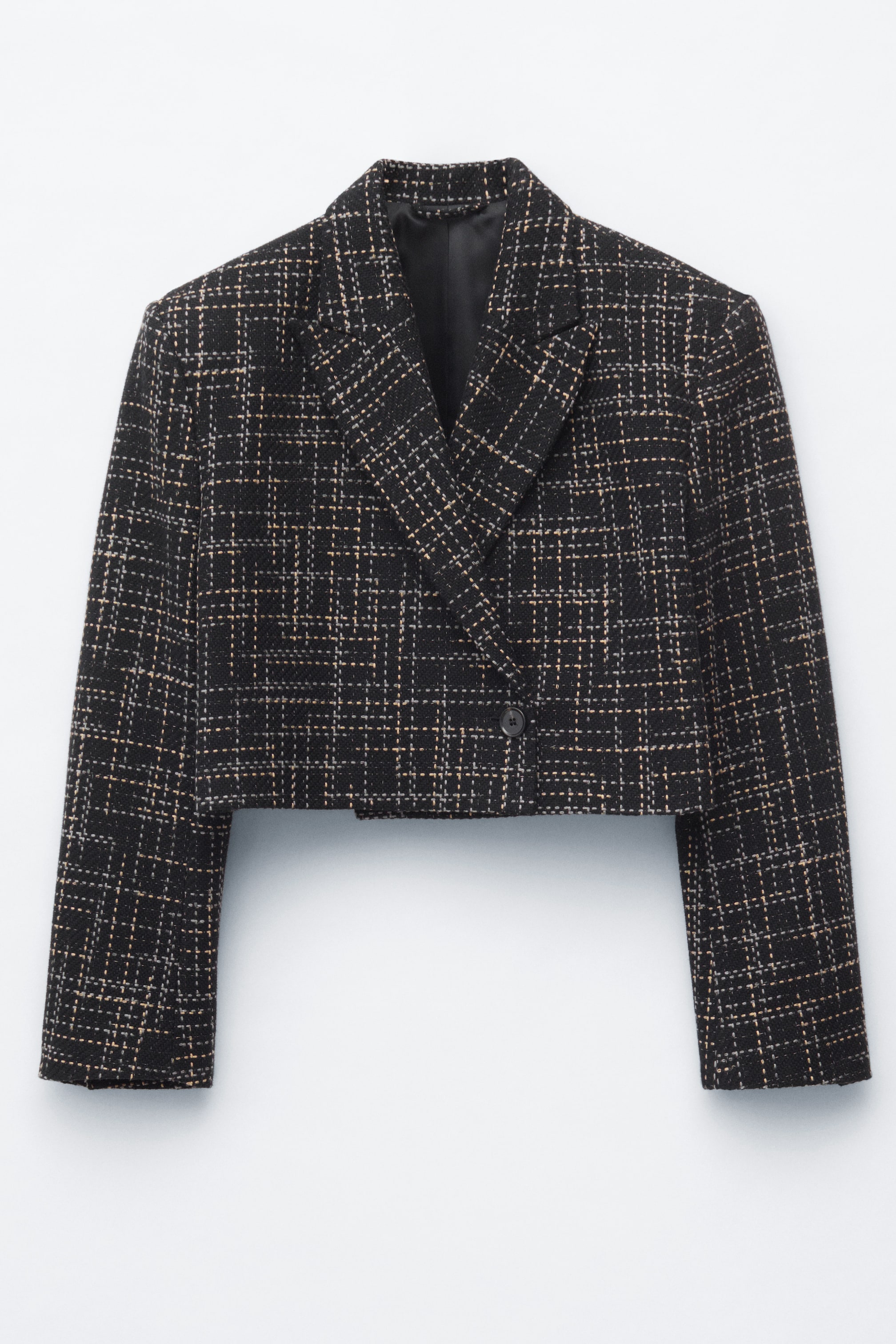 Visualizza l'immagine ingrandita: Una giacca corta presenta la sua parte anteriore, realizzata in un tessuto stile tweed nero con un motivo a quadri con linee marrone chiaro e bianche. È progettata con revers a dente, un davanti doppiopetto e una chiusura con un unico bottone scuro.