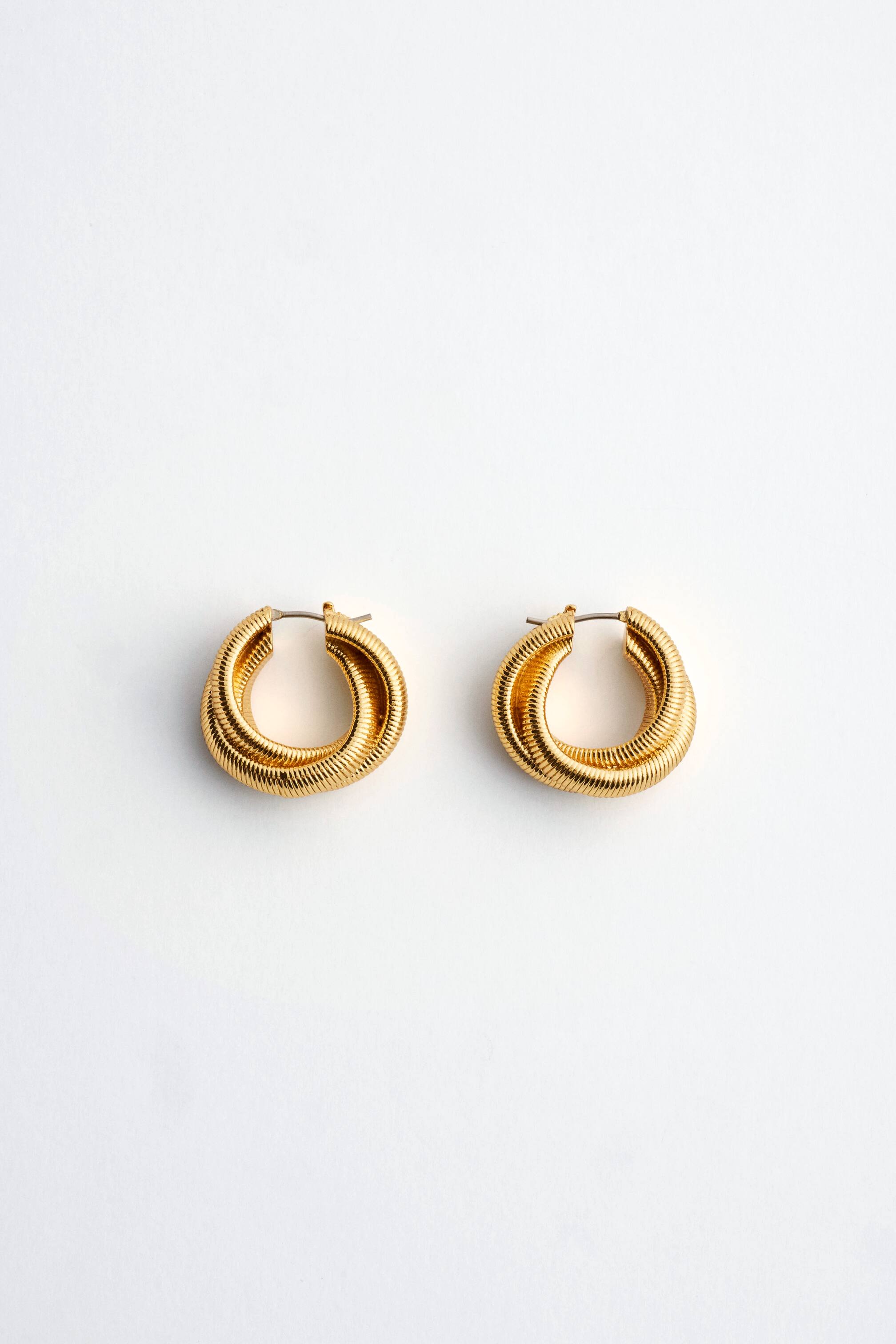 View larger image: Gold-plated hoop earrings are shown front-on, featuring a chunky, twisted design with a finely ribbed, textured surface and a post-clasp fastening.