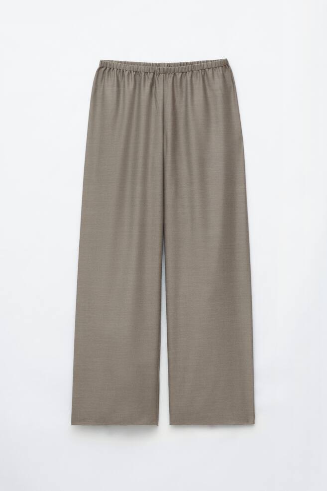 These taupe-brown pull-on trousers are shown from the front, featuring a relaxed wide-leg silhouette and an elasticated waistband. The lightweight fabric drapes smoothly to create a clean, seam-free appearance down to the hems. - 1