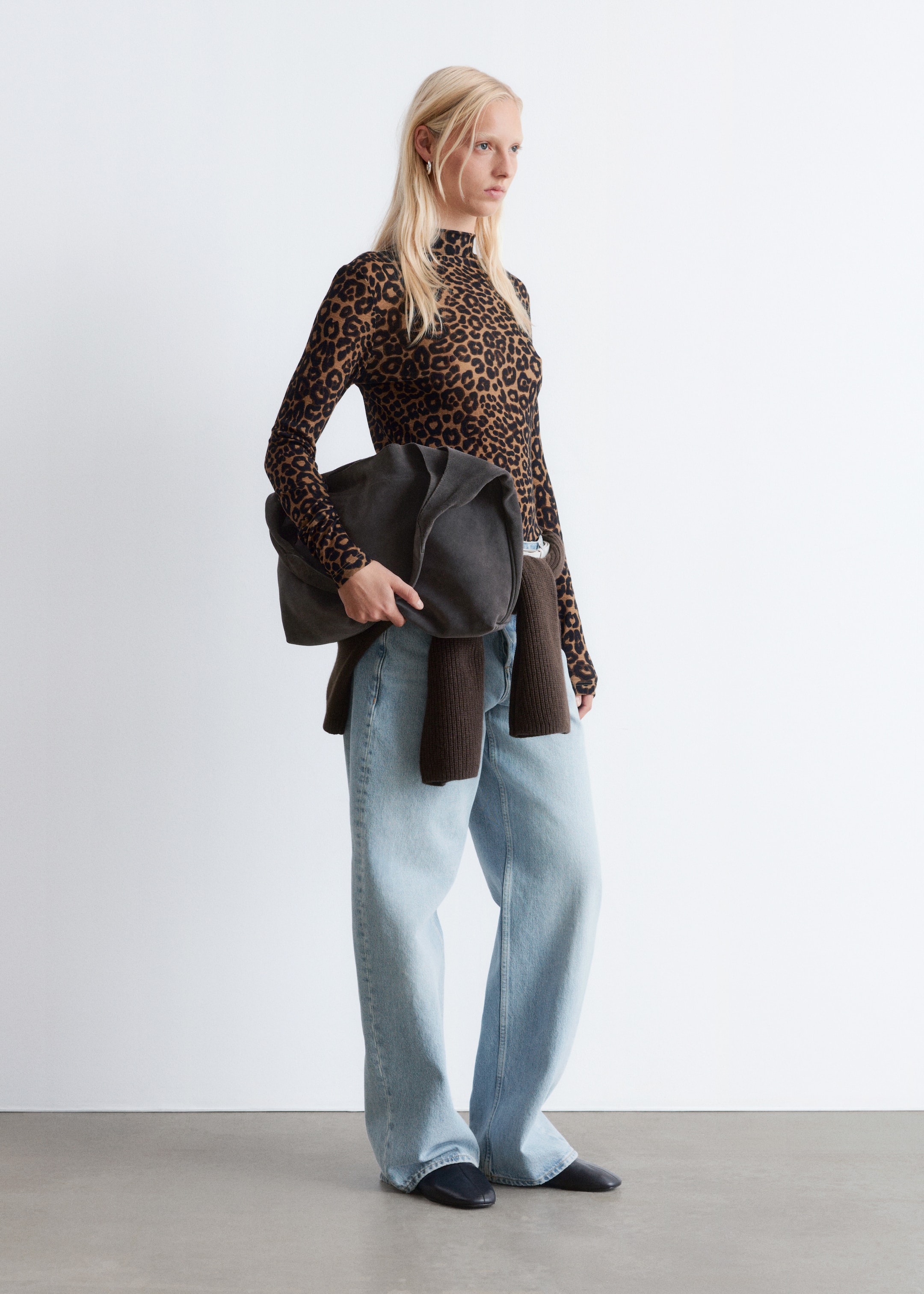 Visa större bild: En leopardmönstrad långärmad tröja med polokrage och smal siluett bärs av modellen, stylad med en mörkbrun tröja knuten runt midjan och ljusblå jeans med vida ben.