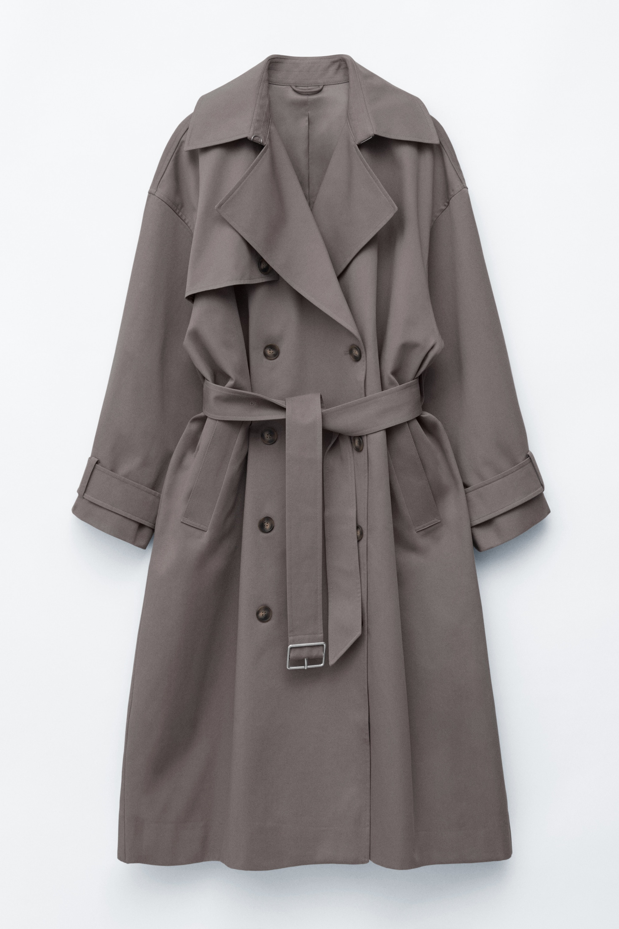 View larger image: The grey-brown trench coat is showcased from the front, featuring a double-breasted design with dark buttons. It displays wide lapels, a fabric belt cinching the waist, welt pockets, and sleeve tabs at the cuffs.