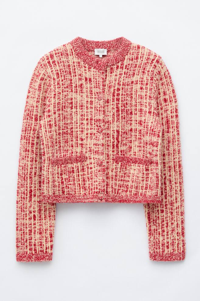 A red and cream textured knit cardigan jacket is shown from the front, featuring a crew neck, a button-front fastening, and two front welt pockets. The garment features a tweed-like grid pattern with solid red ribbed trim detailing the collar, pockets, cuffs and hem. - 1
