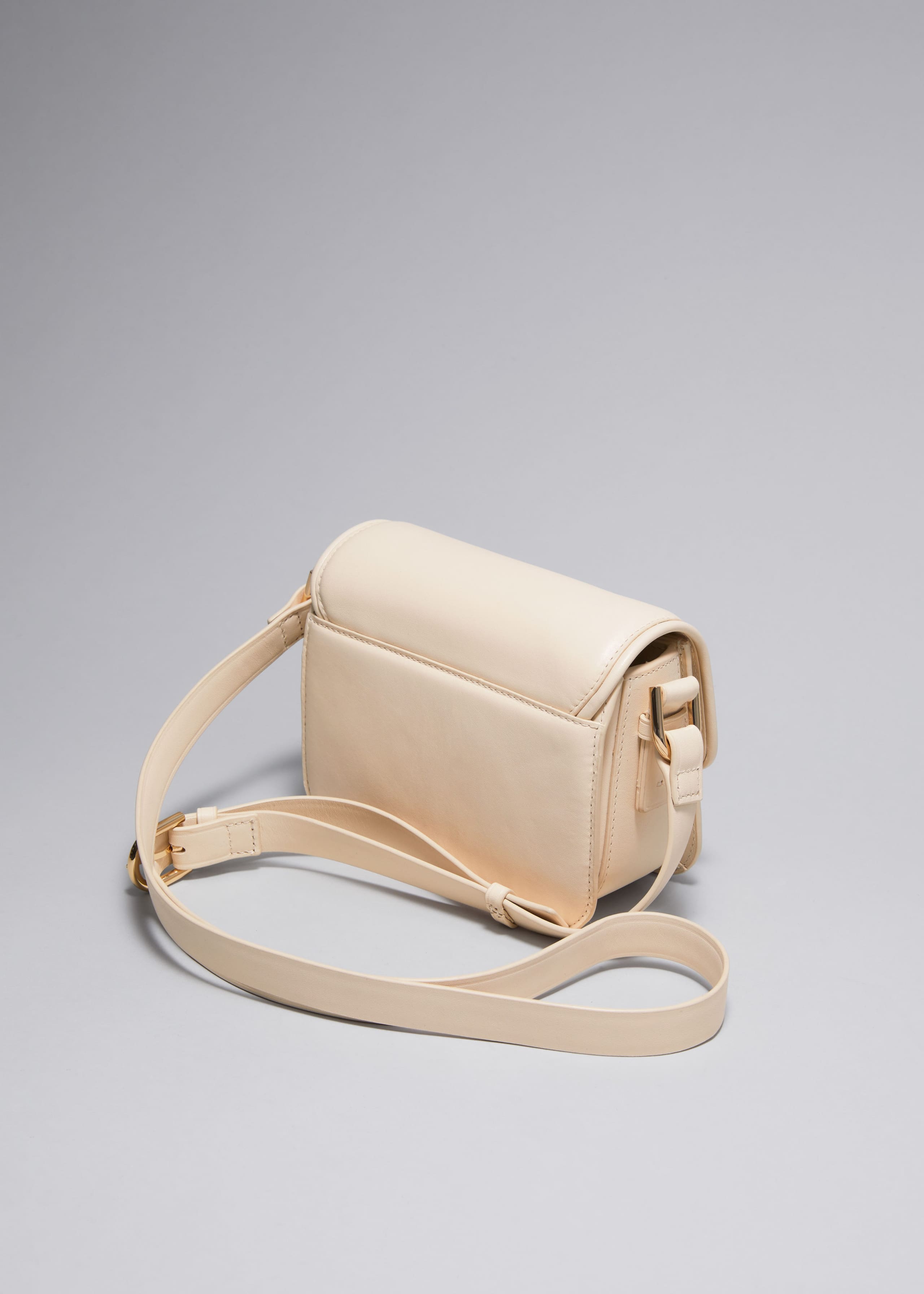 Kleine Ledertasche mit skulpturaler Schnalle - Creme - Stillleben