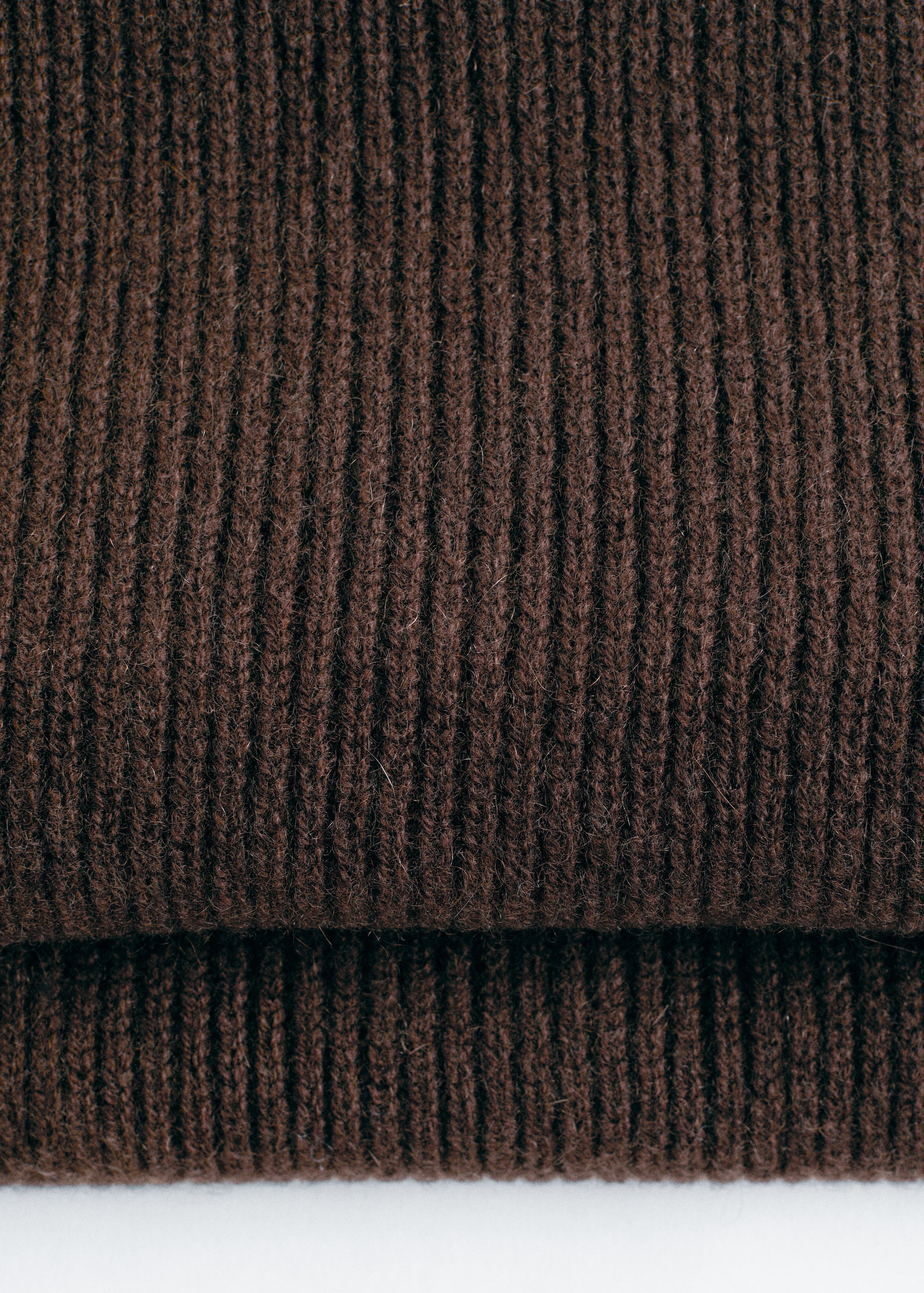 Grösseres Bild ansehen: Ein dunkelbrauner Strickschal ist gefaltet und zeigt sein vertikales Rippmuster über zwei Lagen.