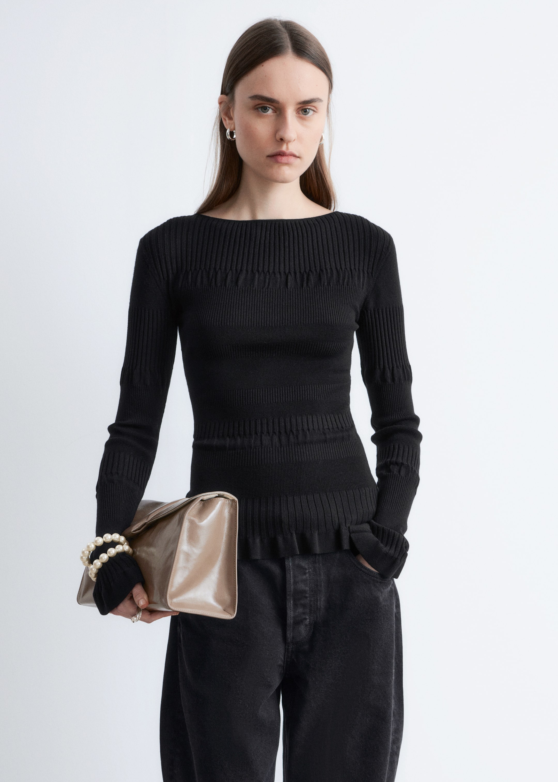 Ver imagen más grande: Un top de punto negro se presenta de frente, con un escote barco, mangas largas y canalé vertical. También muestra bandas texturizadas horizontales en la parte superior del pecho, el torso medio y sobre un dobladillo sutilmente con volantes.