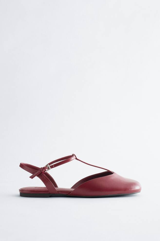 Les ballerines en cuir à talon ouvert se présentent dans une couleur rouge profond, avec un bout arrondi et un dos ouvert. Une fine bride en T s'étend du dessus de la chaussure jusqu'à une bride de cheville ajustable, qui se ferme avec une boucle argentée. - 1