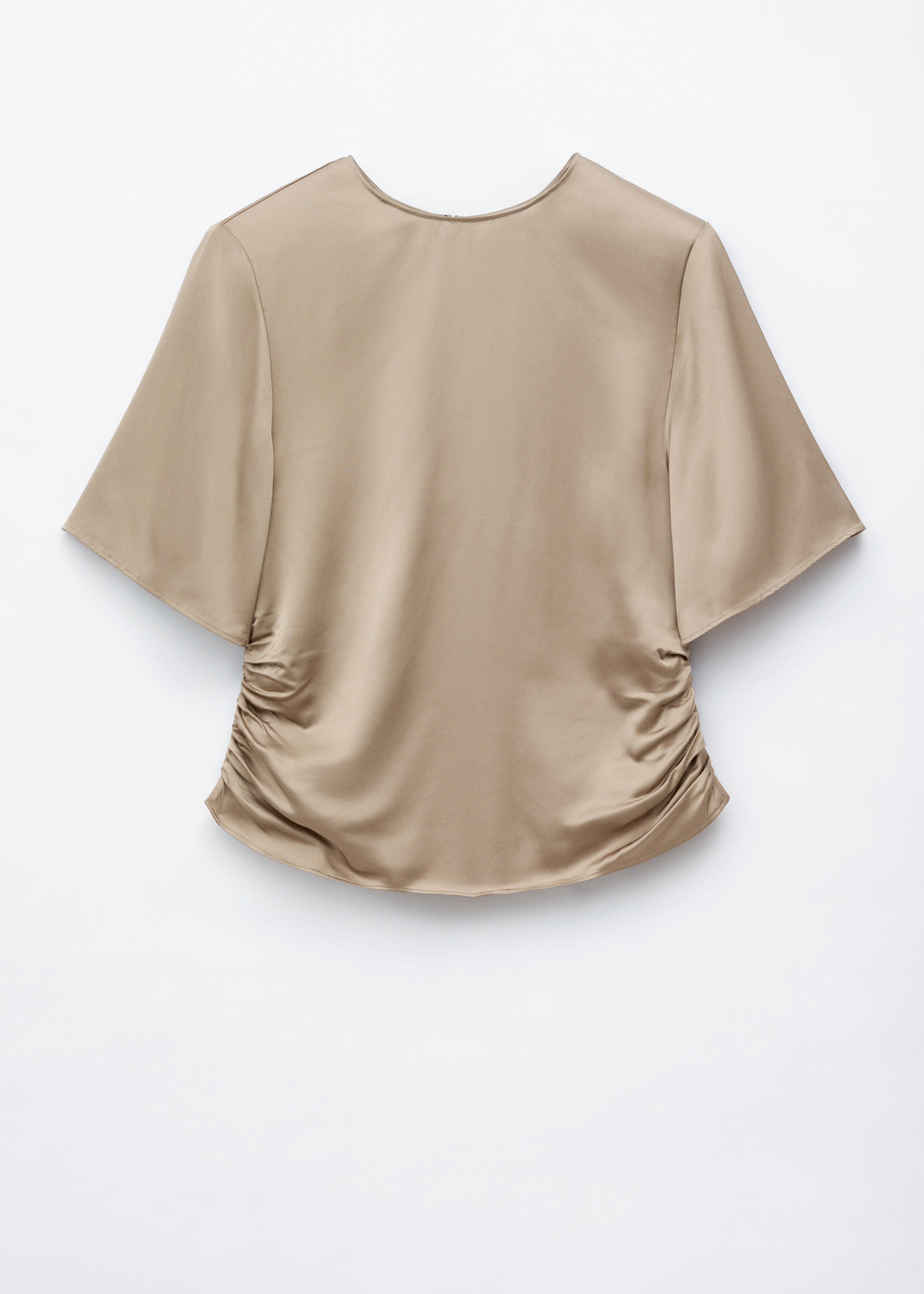 A beige crew neck blouse featuring structured shoulders with subtle gathering is worn by the model. The blouse is styled with large, silver-toned hoop earrings.