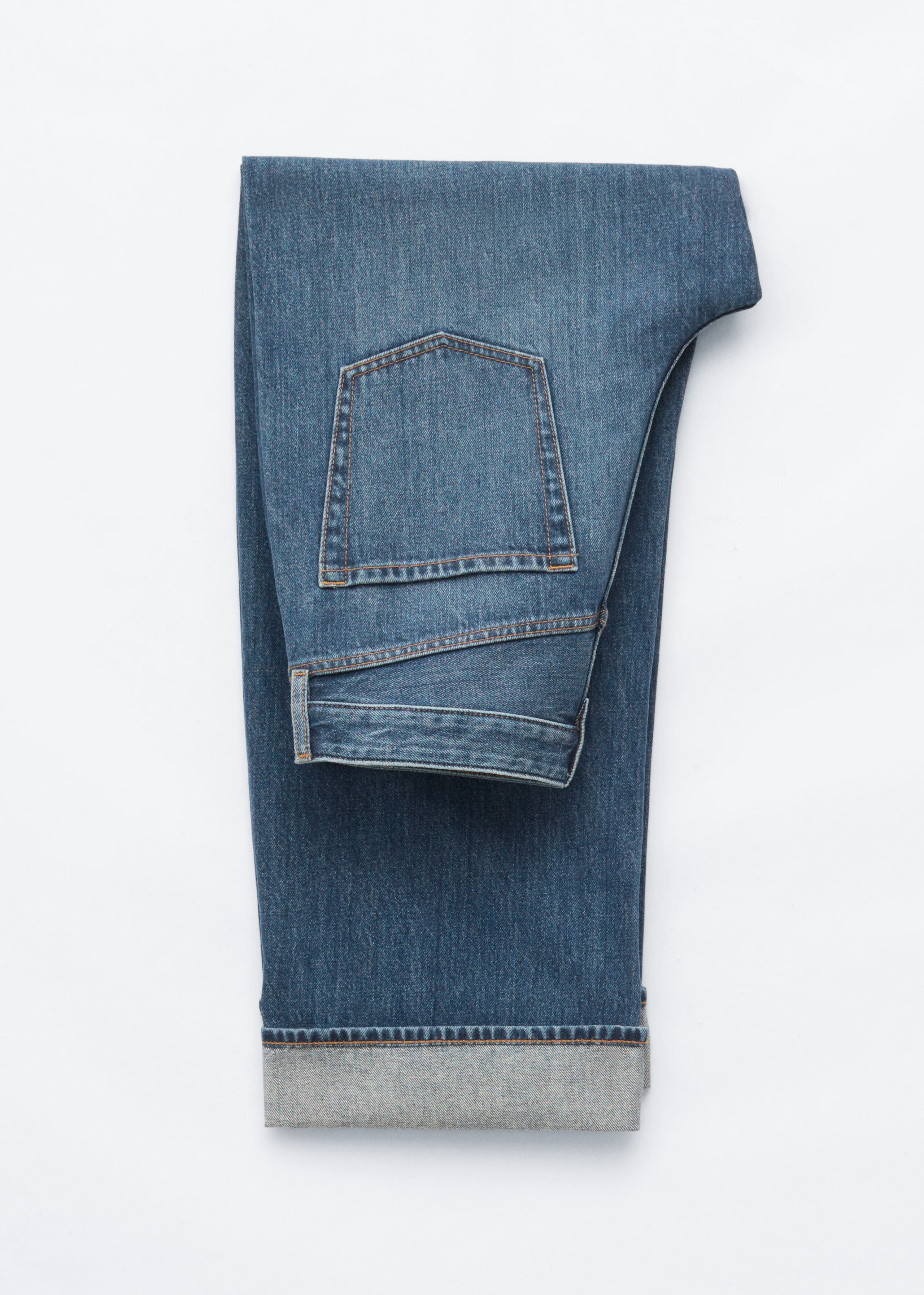 A pair of medium-wash blue jeans is shown folded flat, displaying the back pocket, waistband, and yoke, with the bottom hem turned up to form a wide cuff. The design features classic orange contrast stitching.