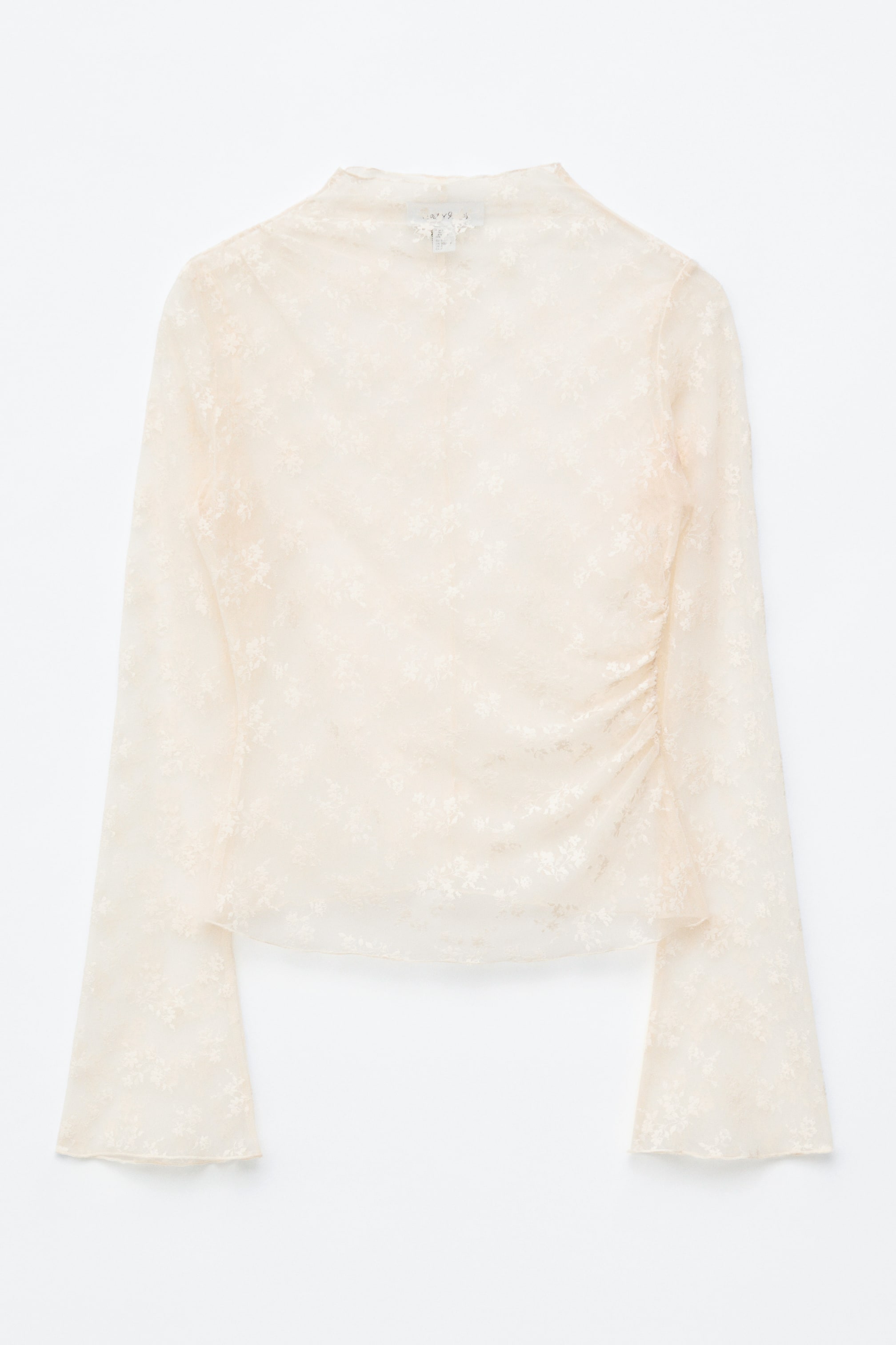 Se større billede: Forsiden af en gennemsigtig, lys beige blondetop viser et dekorativt blomster mønster. Den har en høj hals, lange flæseærmer og rynker langs højre side af torsoen.