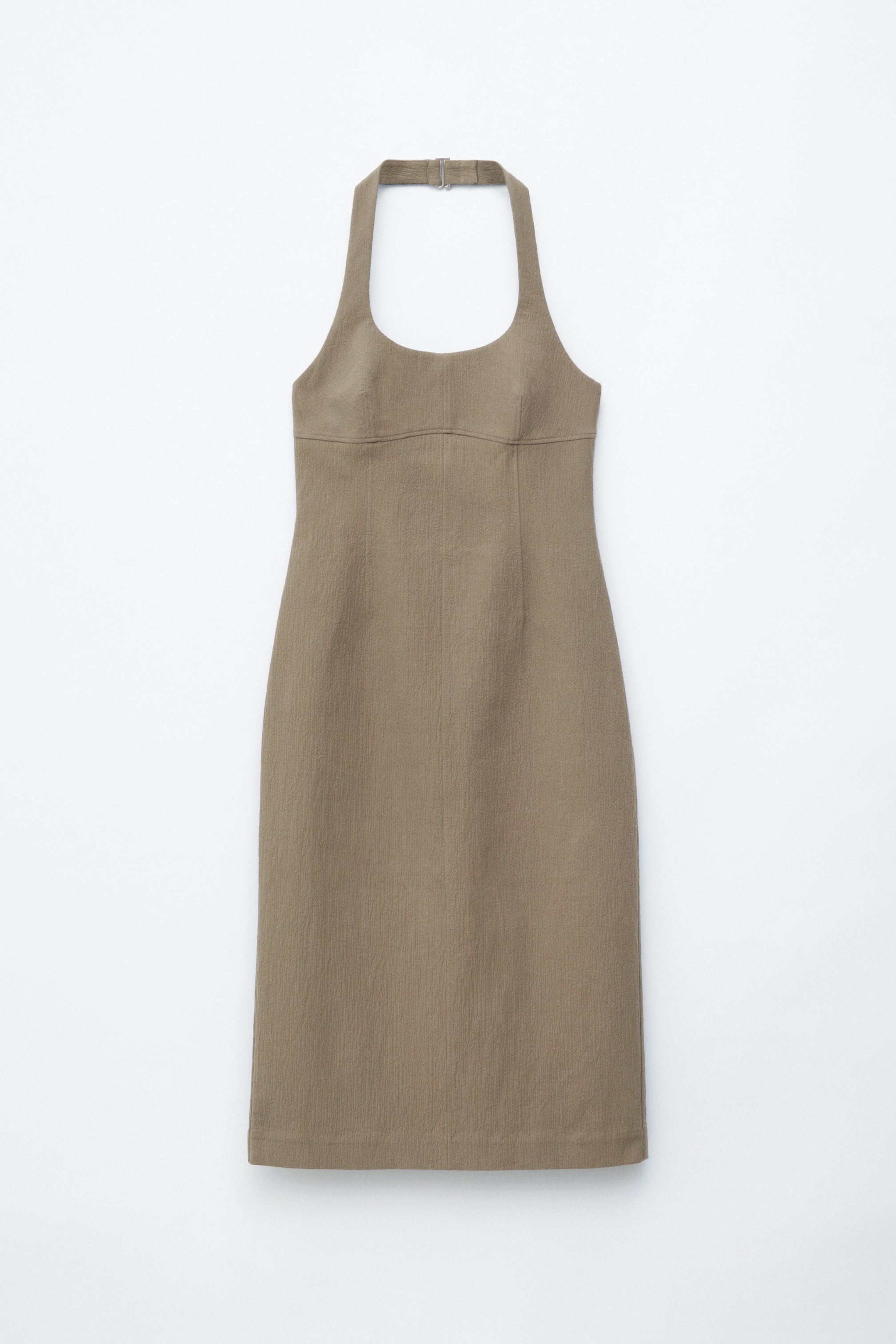 Vis større bilde: En taupe midikjole med en tettsittende silhuett og et åpent, rent halterneck-design sikret med en metallspenne, vist fra fronten. Den er detaljert med synlige sømmer for struktur og viser en subtil stofftekstur.