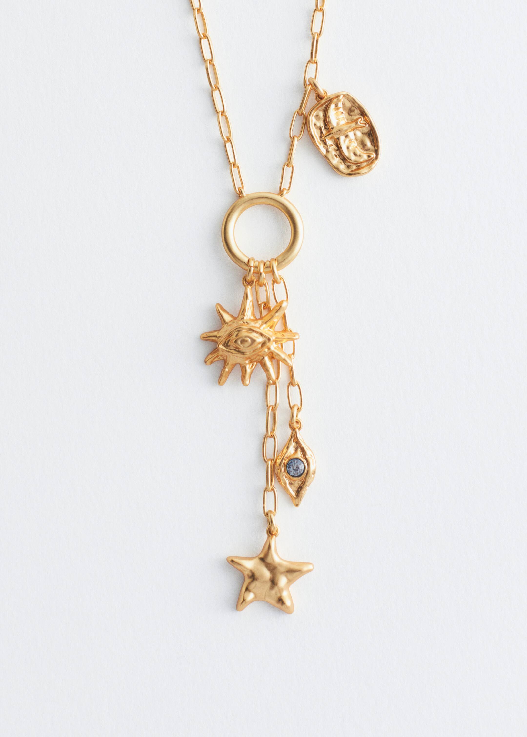 View larger image: A gold-toned lariat necklace is displaying a paperclip chain, featuring a prominent round ring at its front junction. From this ring, multiple textured, figurative charms are hanging, including a sun-shaped charm with an eye, a diamond-shaped charm with a blue stone, and a star-shaped charm, while an additional oval-shaped charm is hanging higher on the main chain.