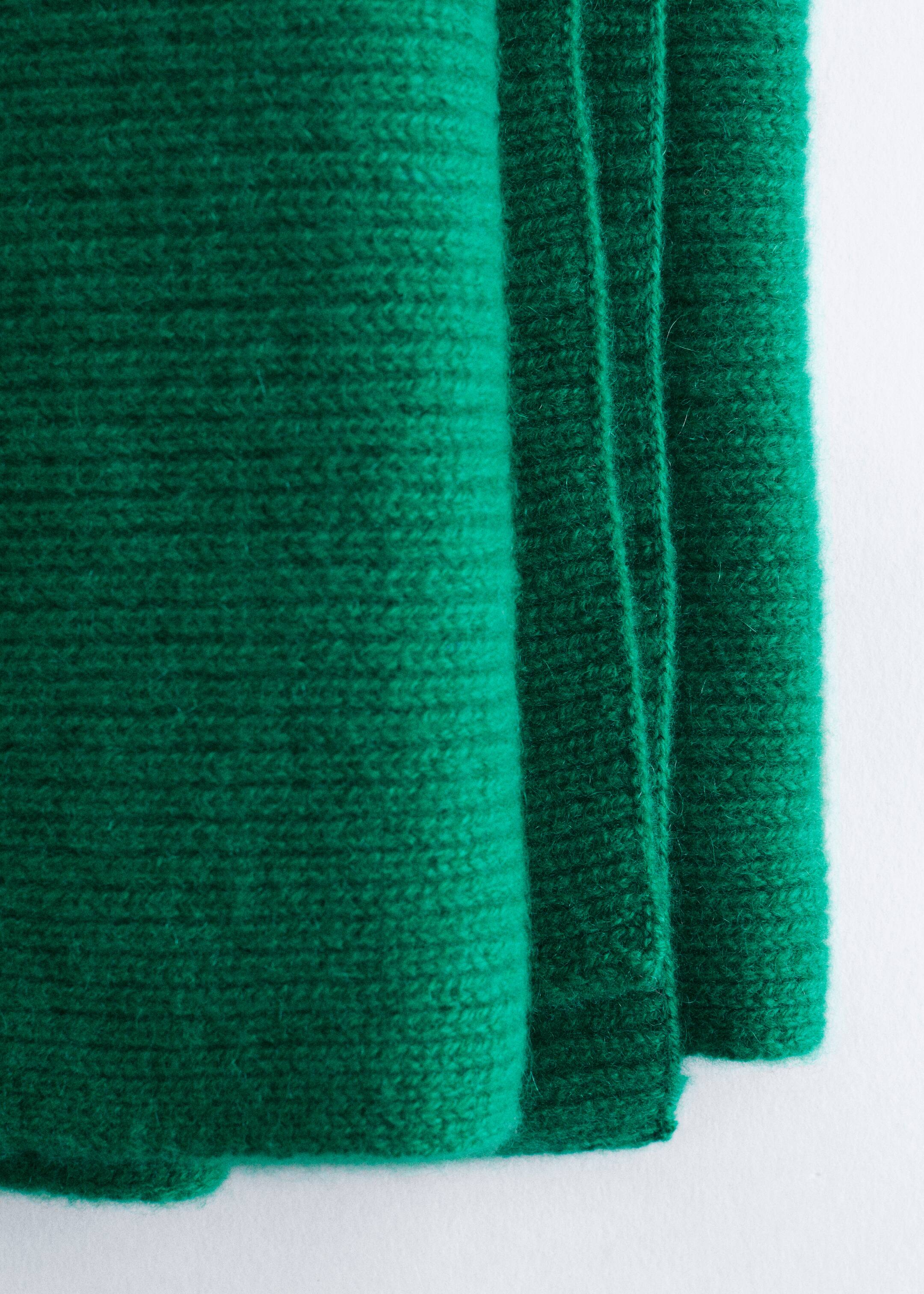 Agrandir l'image: Une écharpe tricotée verte affiche sa texture côtelée. Le tissu doux est plié, montrant plusieurs couches.