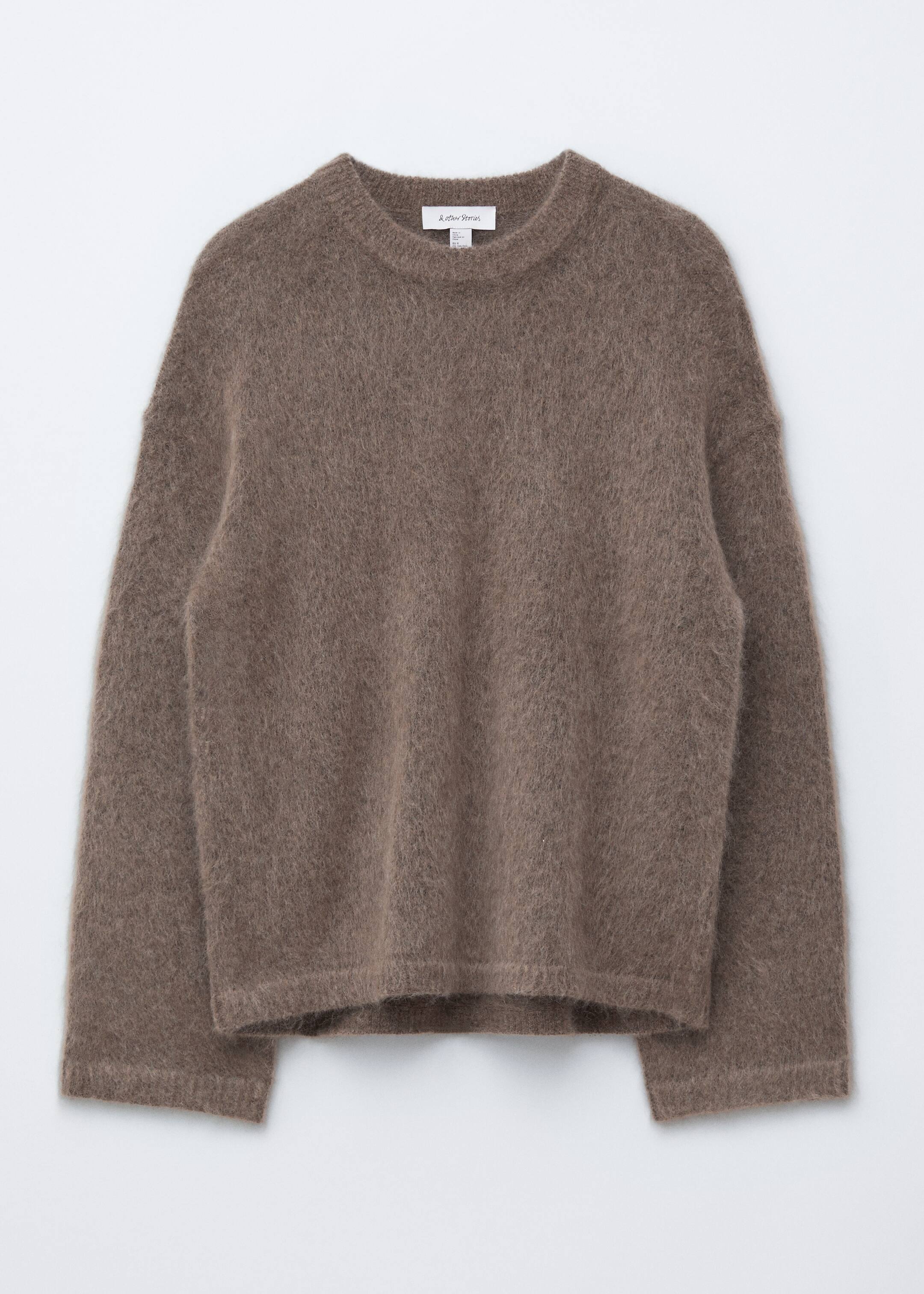 Größeres Bild anzeigen: Ein brauner Langarm-Pullover wird von vorne gezeigt, mit einer entspannten Passform und einer flauschigen Stricktextur. Er ist mit einem gerippten Rundhalsausschnitt, gerippten Bündchen und einem gerippten Saum gestaltet.