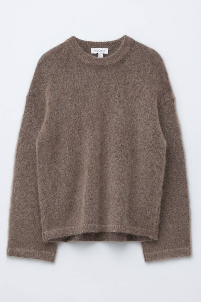 Ein brauner Pullover mit langen Ärmeln wird von vorne gezeigt, mit einer entspannten Passform und einer flauschigen Stricktextur. Er ist mit einem gerippten Rundhalsausschnitt, gerippten Bündchen und einem gerippten Saum gestaltet. - 1