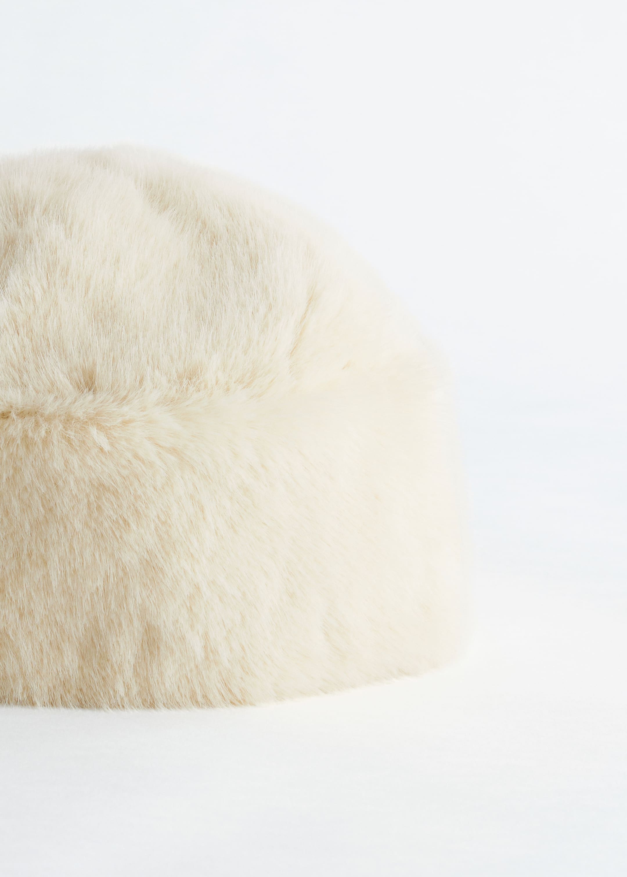 View larger image: A cream-colored, rounded faux fur hat is presenting its front, featuring a soft, long-pile texture and a visible central seam across its crown.