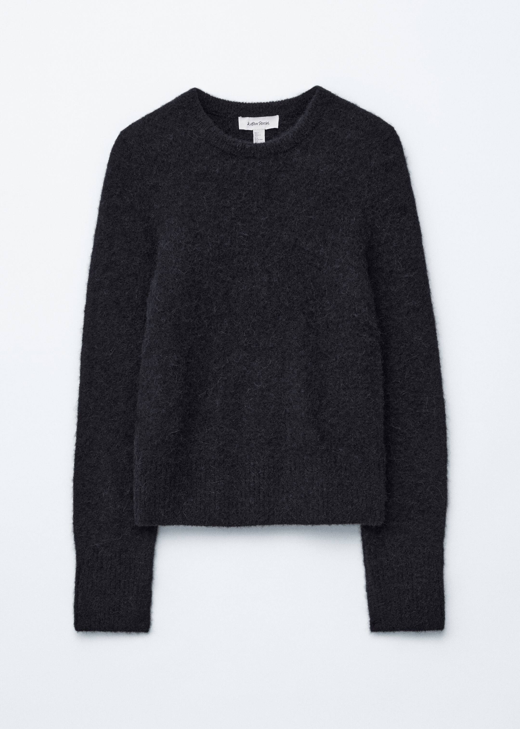 Agrandir l'image: Un pull en tricot gris foncé est présenté de face, avec une texture douce et duveteuse, un col rond, des manches longues et des finitions côtelées subtiles aux poignets et à l'ourlet.
