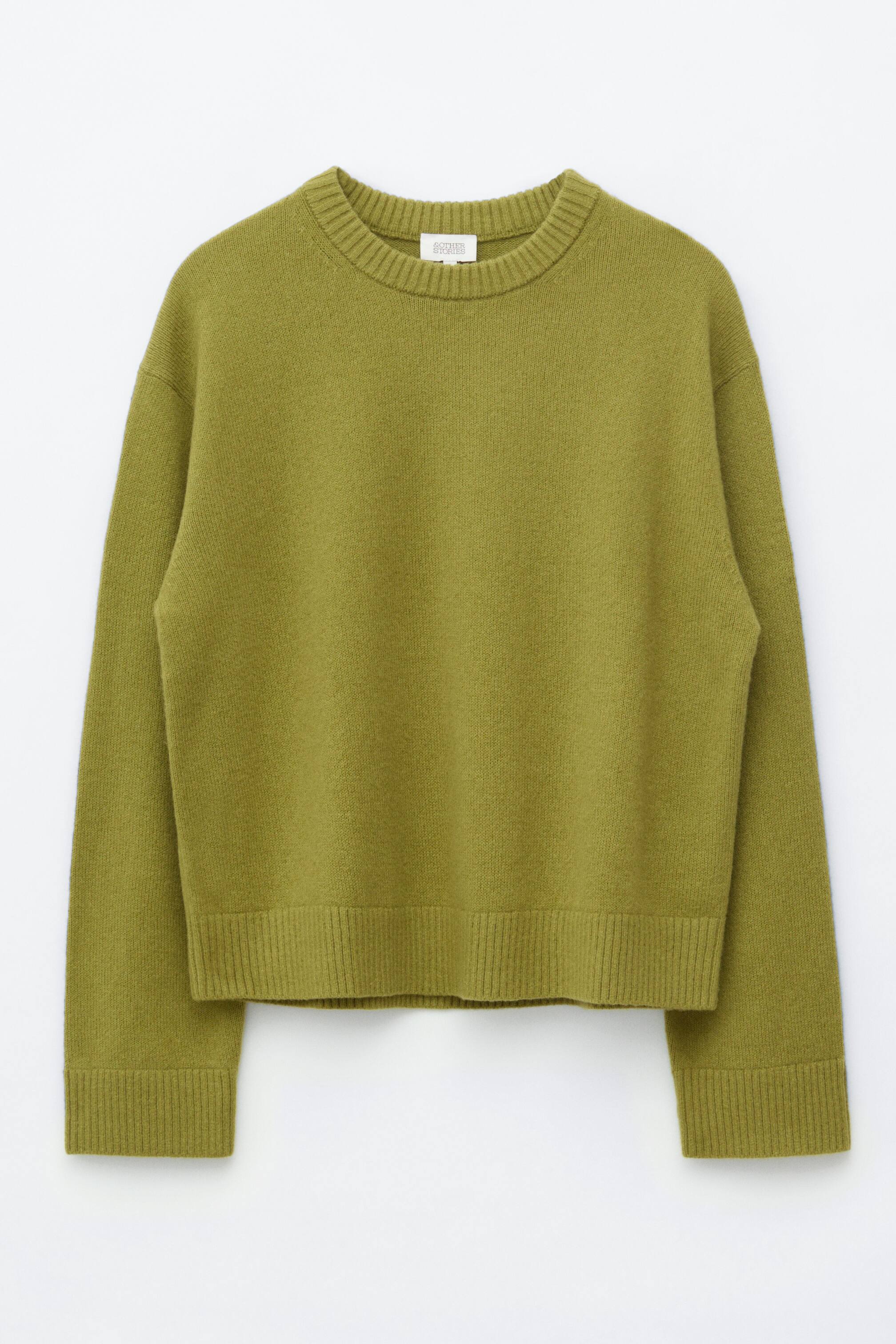 View larger image: The green knitted jumper is displayed front-facing, showcasing a boxy fit with set-back shoulders and ribbed trims on the neck, cuffs, and hem.