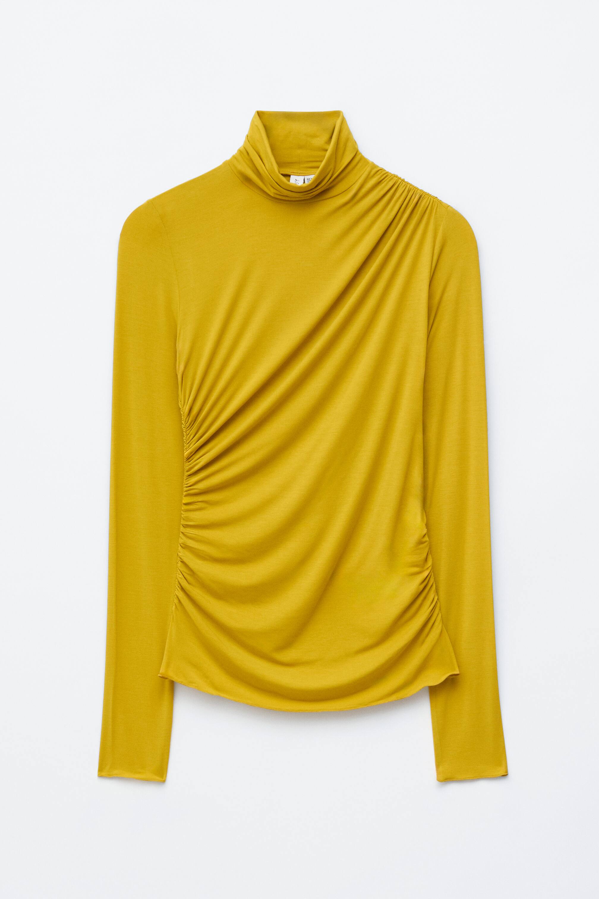 Se større billede: FRONT visning af en gylden gul top. Den har en draperet rullekrave og omfattende rynkning, der flyder fra højre skulder diagonalt hen over fronten og ned langs venstre side, hvilket skaber en all-over draperet effekt. Toppen er designet med ekstra lange ærmer, en slank pasform og en asymmetrisk kant, alt sammen afsluttet med overlockede kanter.