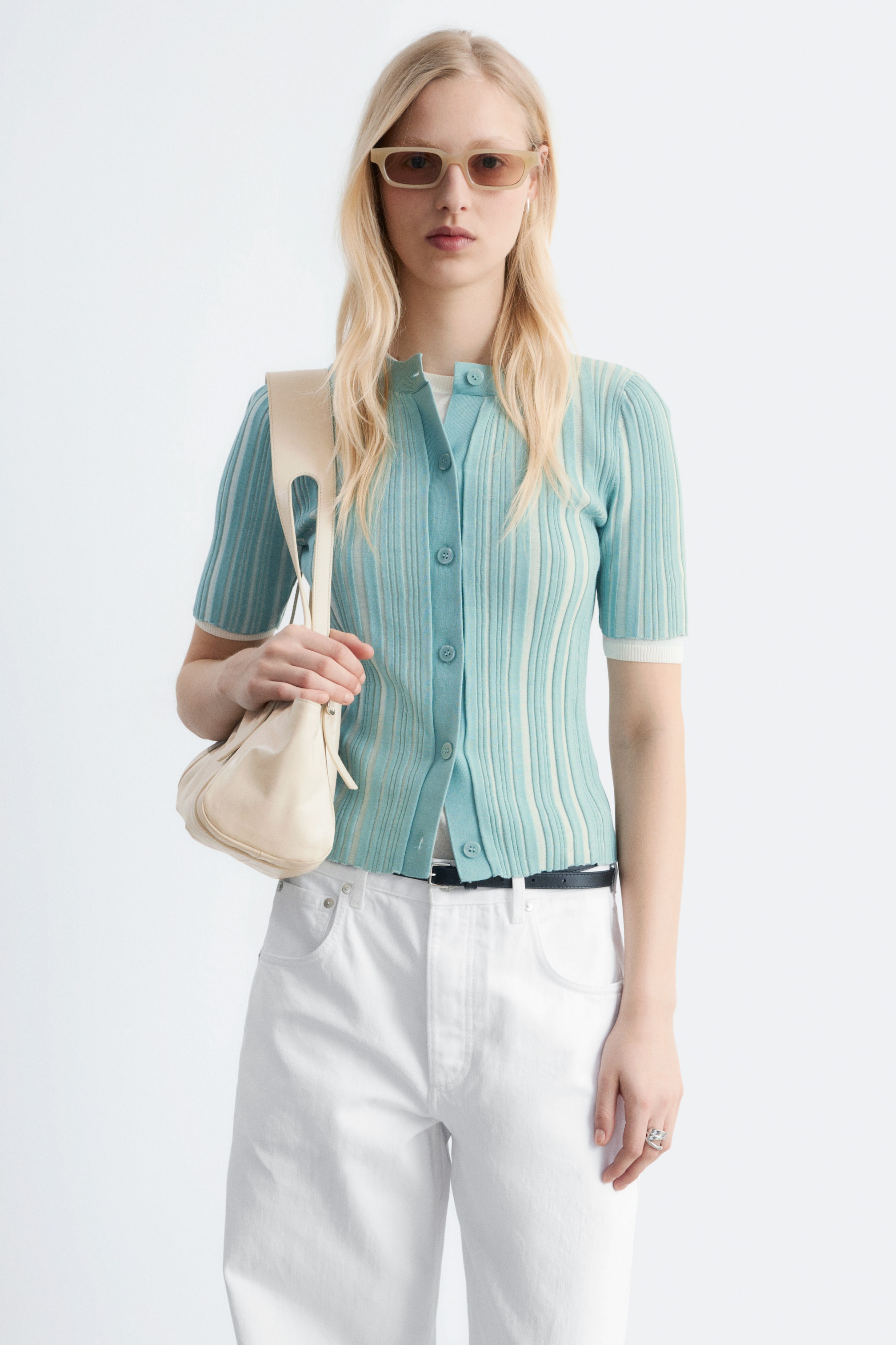 Se større billede: En kortærmet ribstrikket cardigan præsenteres forfra og har skiftevis lodrette striber i lyseblågrøn og creme. Den har en rund halsudskæring og en fuld knaplukning med matchende lyseblågrønne knapper og bæres over en hvid t-shirt.