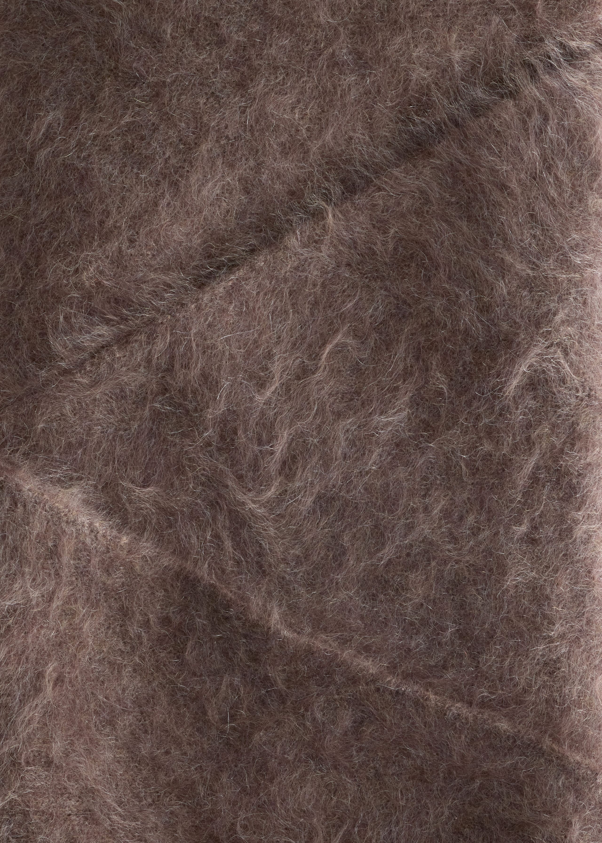 A brown brushed knit fabric displays a highly textured, fuzzy, and hairy surface with long, fine fibers. Subtle diagonal seams run across the plush material, defining its structure.