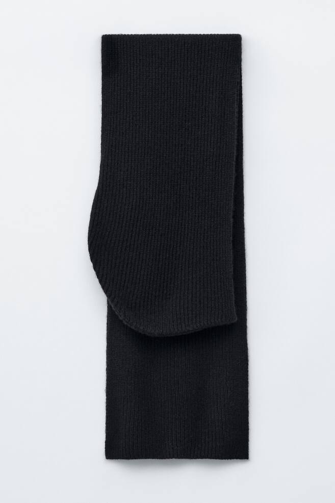 A black ribbed knit hooded scarf is lying flat, showcasing its integrated hood with a distinct rounded shape. - 1