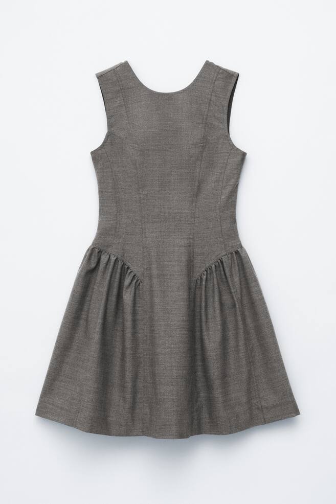 A grey sleeveless dress is presenting its back view. The dress features a scoop back neckline and a fitted bodice with vertical shaping seams. The flared skirt gathers at the waistline, creating soft pleats that extend downwards. - 1