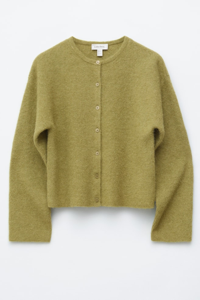 FRONTANSICHT eines langärmeligen, olivgrünen Cardigans mit Rundhalsausschnitt und sechs natürlich getönten Knöpfen, die mittig vorne geschlossen werden. Der Cardigan präsentiert eine weiche, dezent gerippte Strickstruktur und einen verkürzten Saum. - 1
