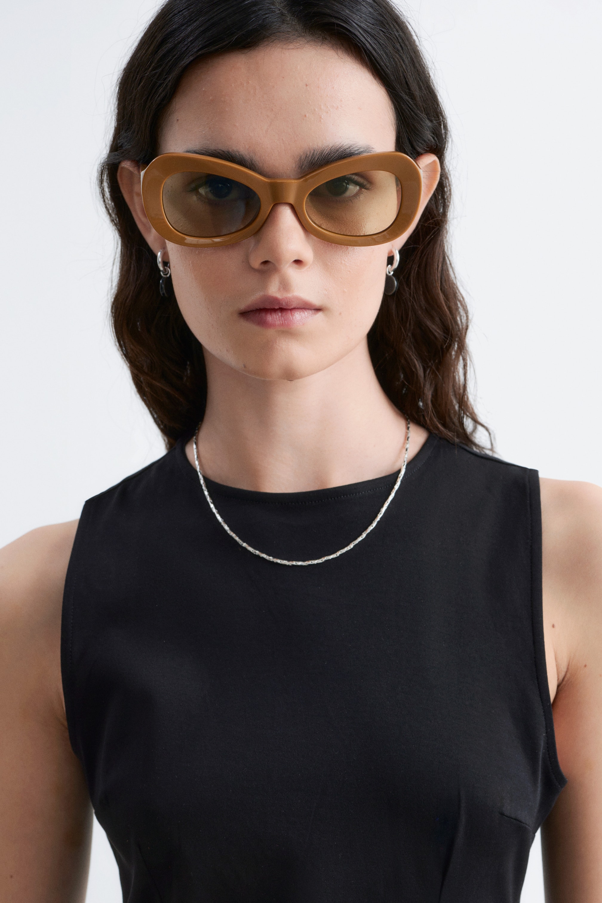 Agrandir l'image: Lunettes de soleil marron avec des montures ovales épaisses et des verres teintés jaunes portées de face.