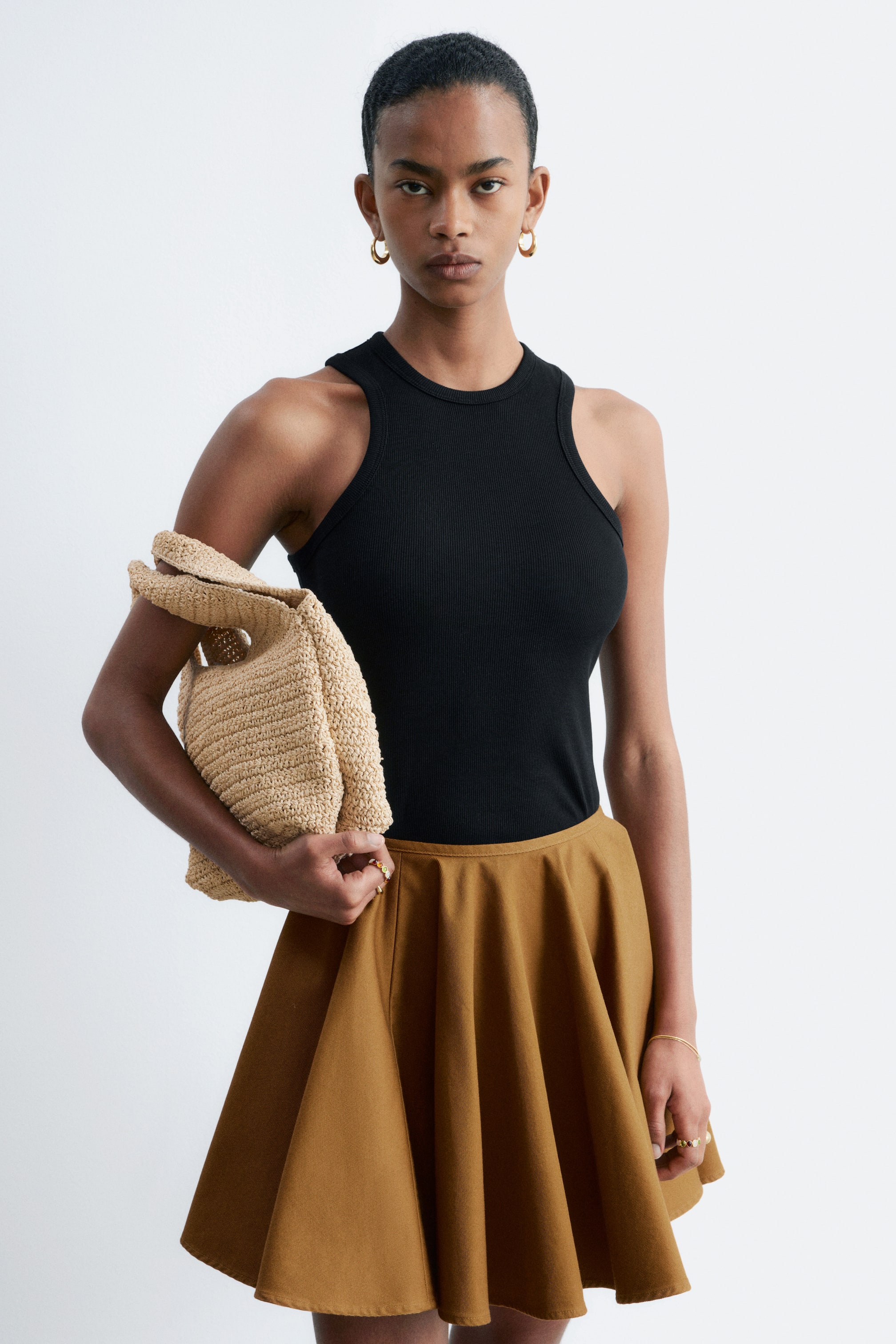 Grösseres Bild ansehen: Der braune Rock zeigt einen ausgestellten A-Linien-Schnitt mit weichen, fließenden Falten, die sich von der Taille bis über das Knie erstrecken.