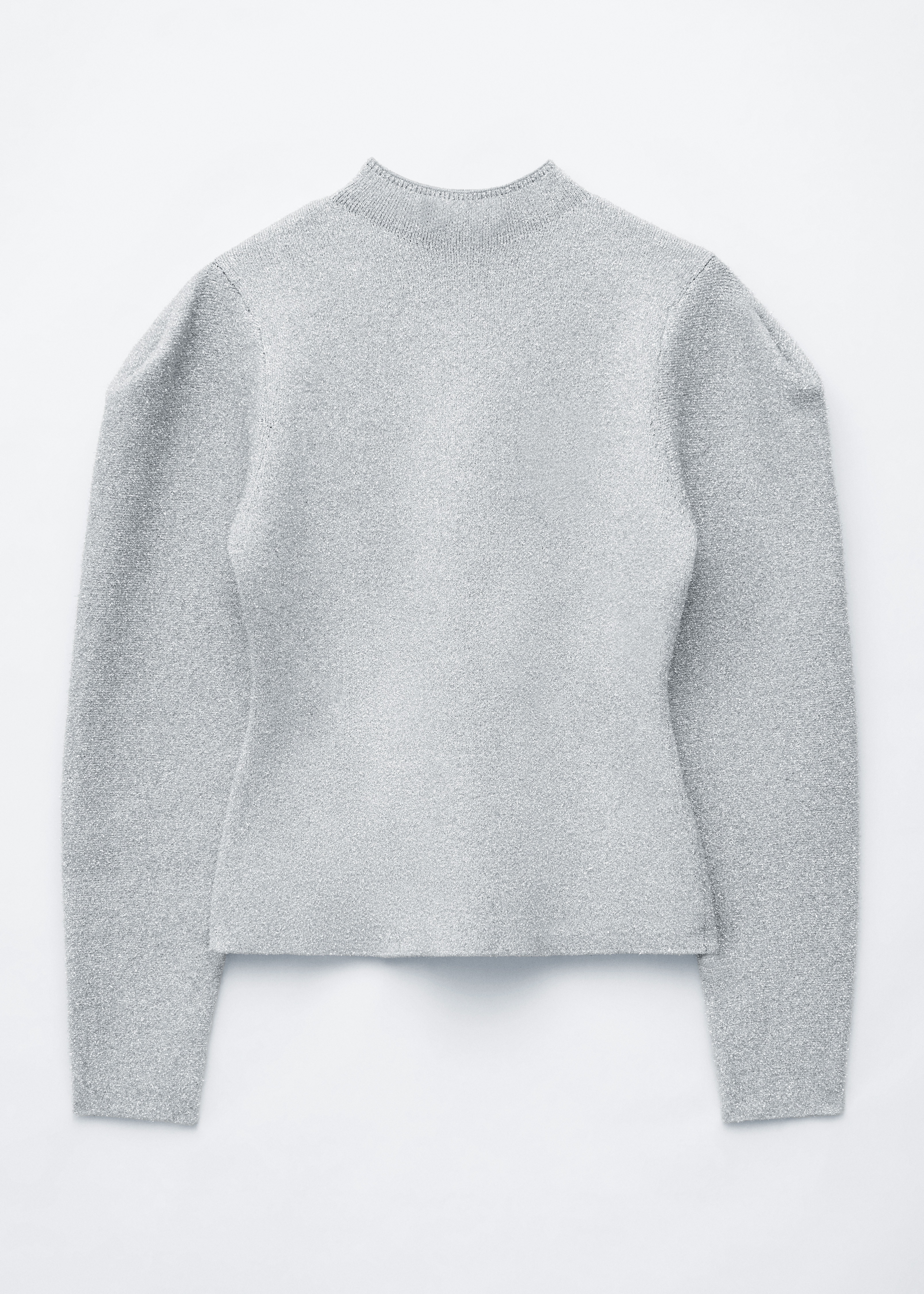 A modelo estÃ¡ a usar uma camisola de malha azul-claro com brilho, com gola alta e ombros estruturados e plissados. A camisola de corte justo estÃ¡ metida dentro de uns jeans cinzento-escuros.