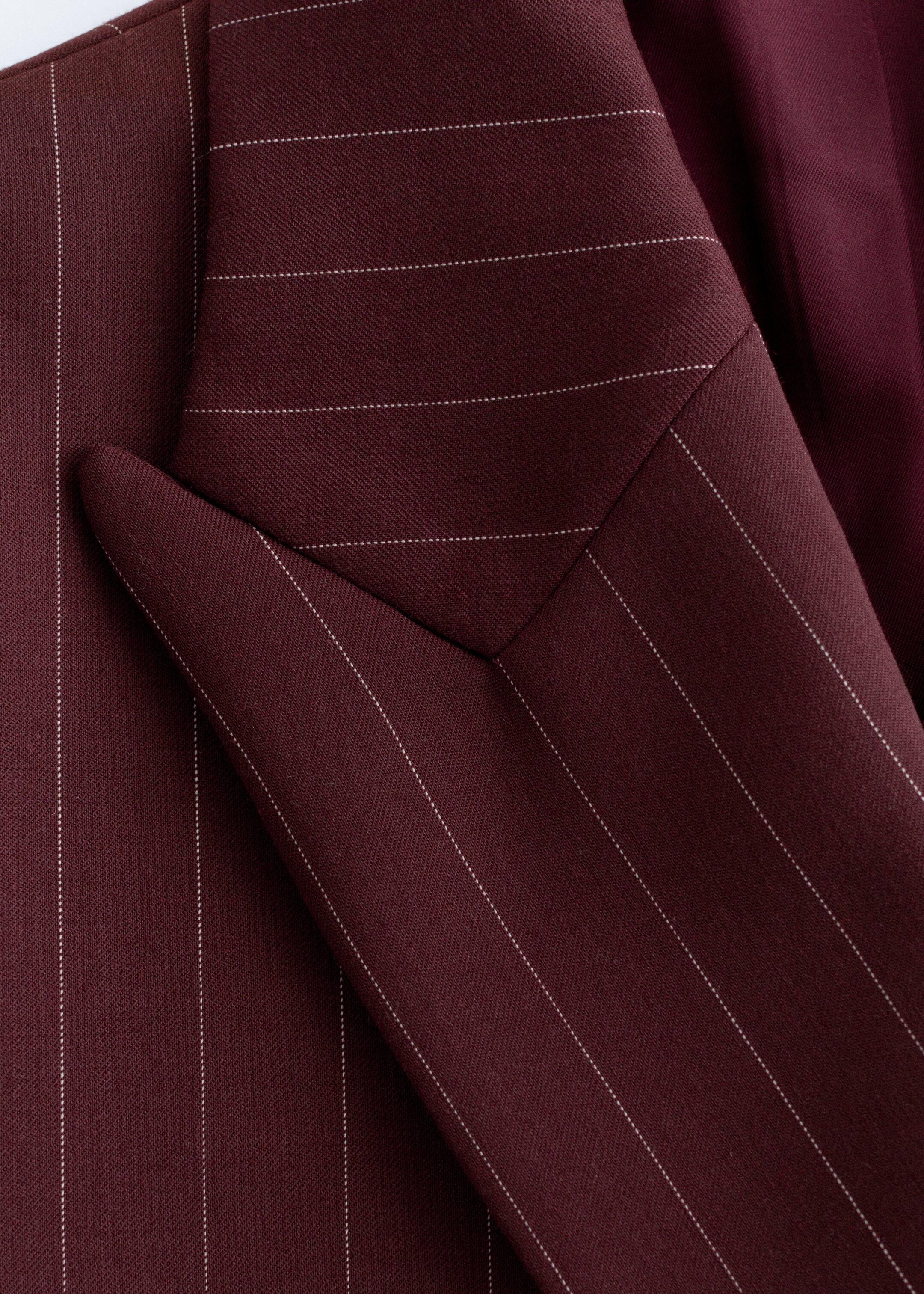 Agrandir l'image: Un gros plan d'un blazer bordeaux montre sa construction sur mesure. De fines rayures blanches courent dans différentes directions sur des panneaux de tissu précisément cousus.