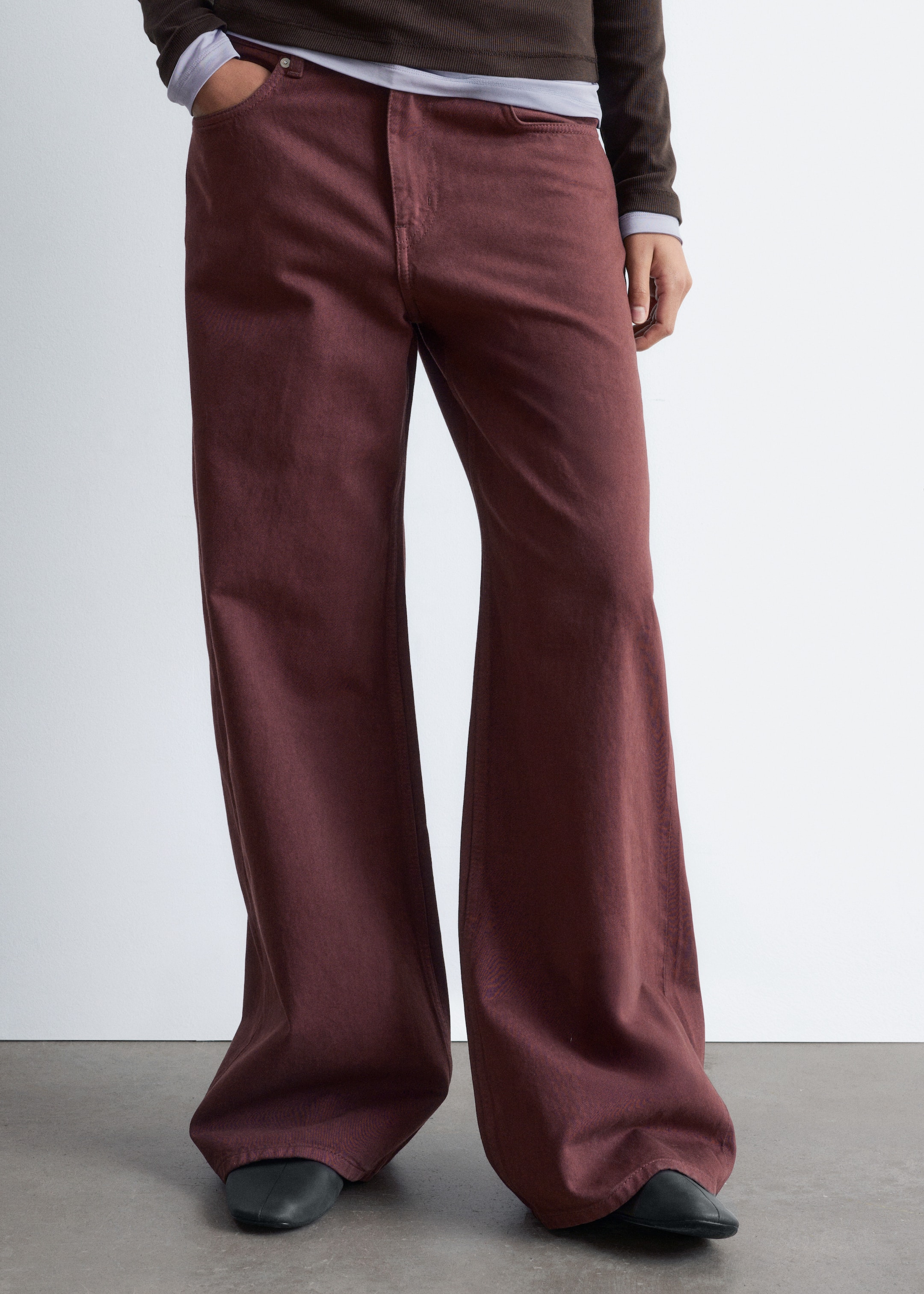 Ver imagen más grande: Los pantalones de pierna ancha son de un color marrón rojizo oscuro, ensanchándose significativamente desde el muslo y cubriendo los zapatos del usuario. Se presentan desde un ángulo frontal, con una cremallera visible y bolsillos delanteros.
