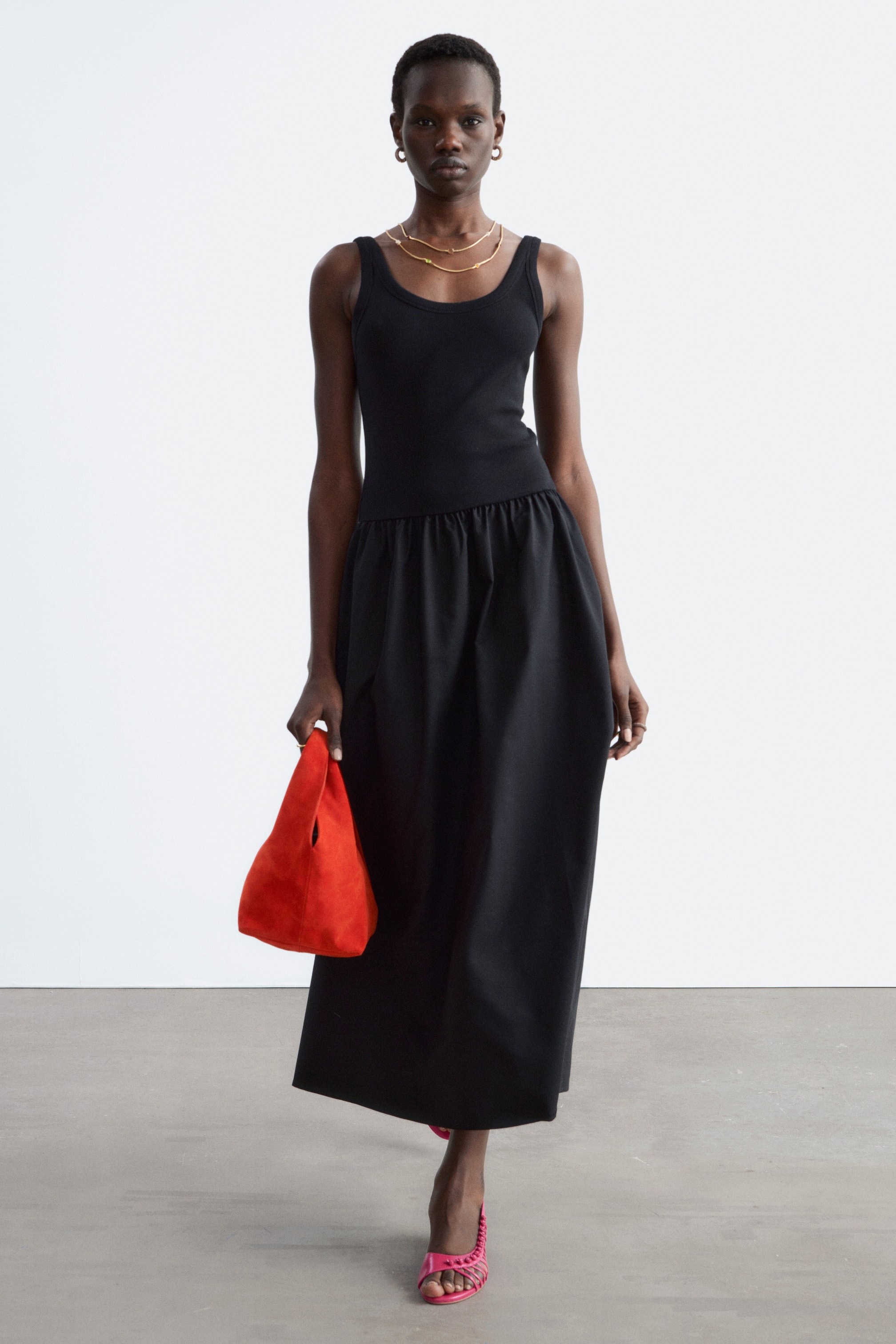 Zobraziť väčší obrázok: Čierne šaty s priliehavým, rebrovaným tielkovým živôtikom s okrúhlym výstrihom, ktorý prechádza do stiahnutého pásu a plnej, stredne dlhej sukne, sú otočené dopredu.