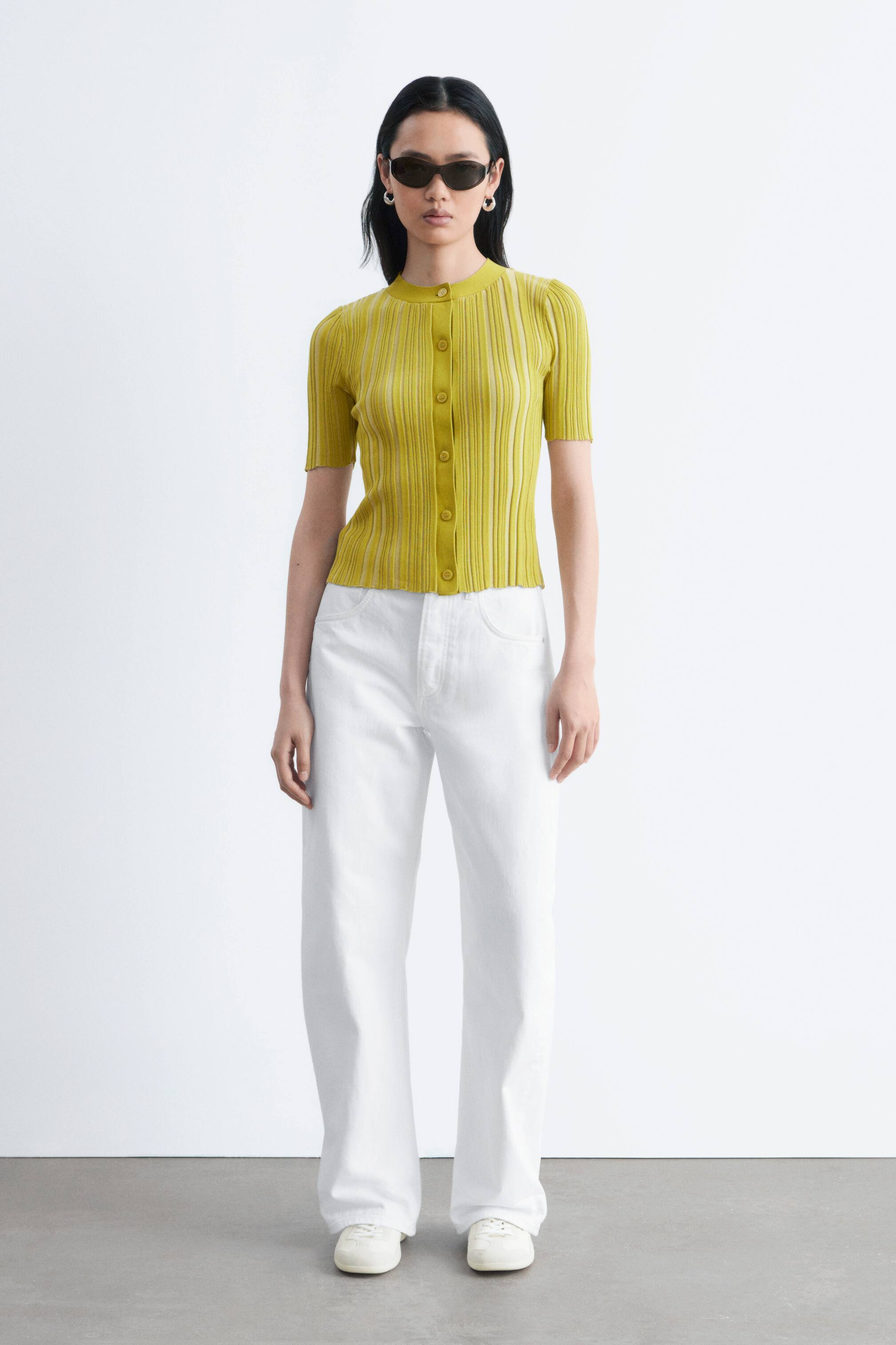 Ver imagem maior: Um top de malha amarelo com mangas curtas caneladas apresenta uma gola redonda e um fecho frontal completo com botões. Exibe uma silhueta ajustada vista de frente.