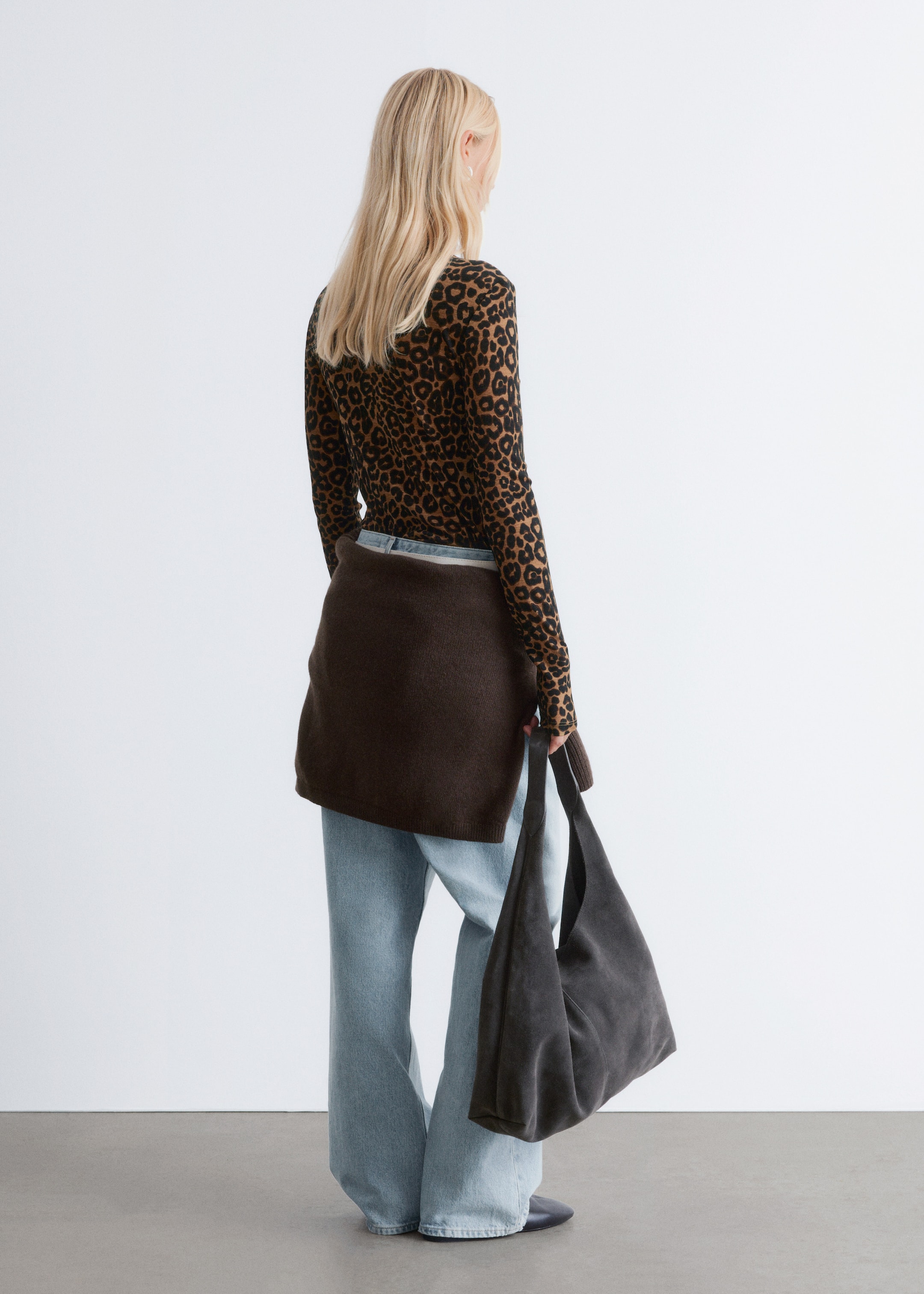 Visa större bild: Den tryckta långärmade mockapolo-tröjan, med ett leopardmönster och en smal siluett, bärs av modellen. Den är lagrad under en brun stickad tröja, som bärs över ljusa jeans.
