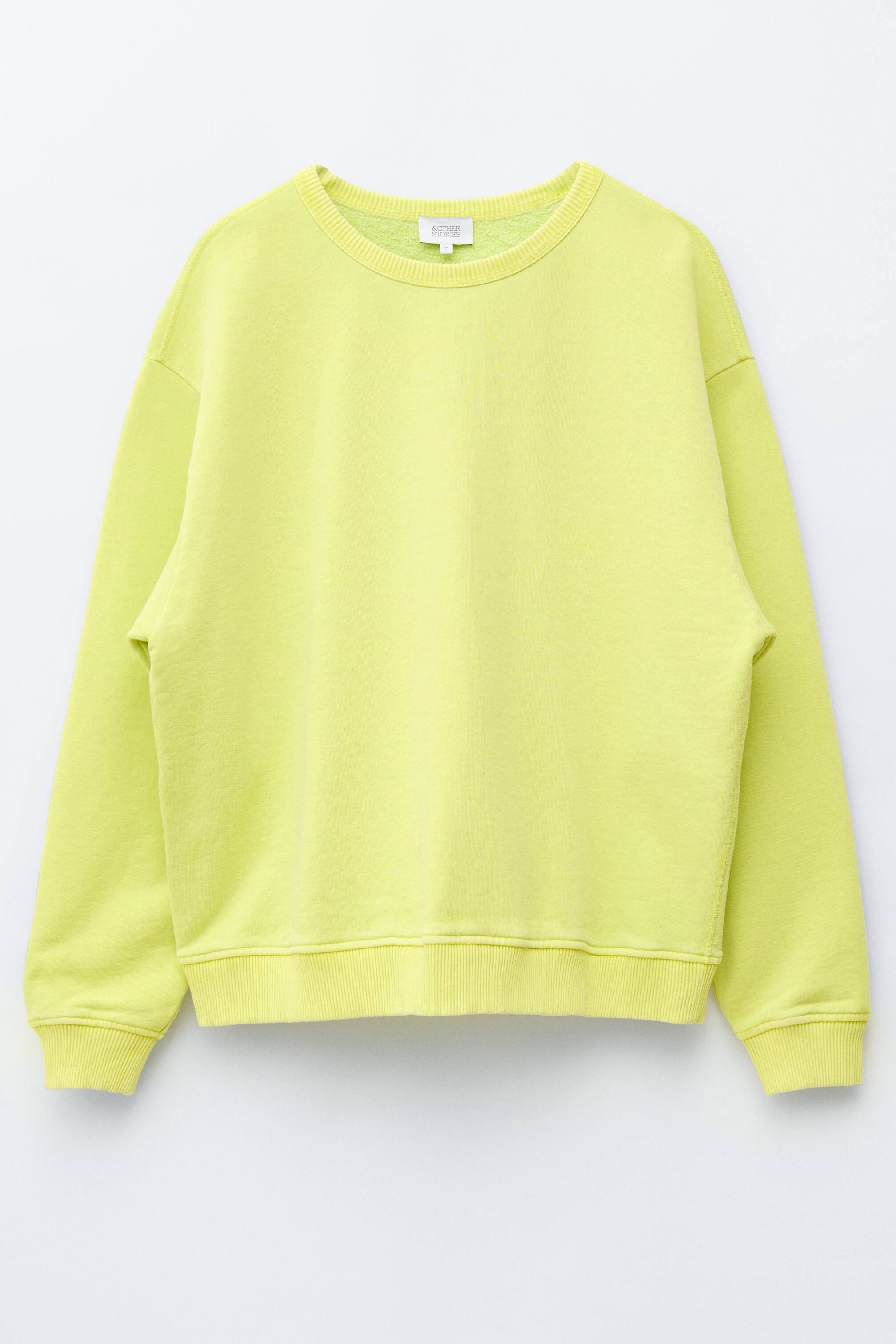 Se større billede: En limegrøn oversize sweatshirt vises fra forsiden, med en ribbet rund hals, sænkede skuldre og ribbede manchetter og kant.
