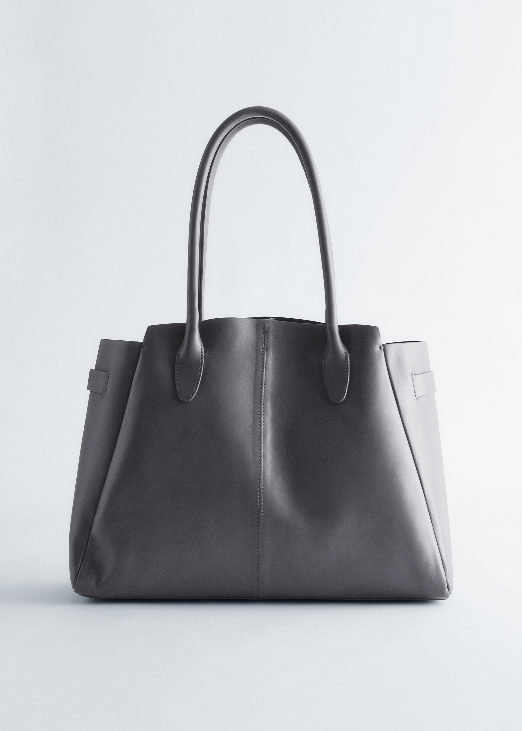 Visualizza immagine più grande: Una borsa tote grigio scuro viene presentata dal davanti, mostrando una texture liscia e opaca. Presenta due manici superiori arcuati e pannelli laterali con soffietto strutturato, ognuno con una piccola linguetta orizzontale in cima.