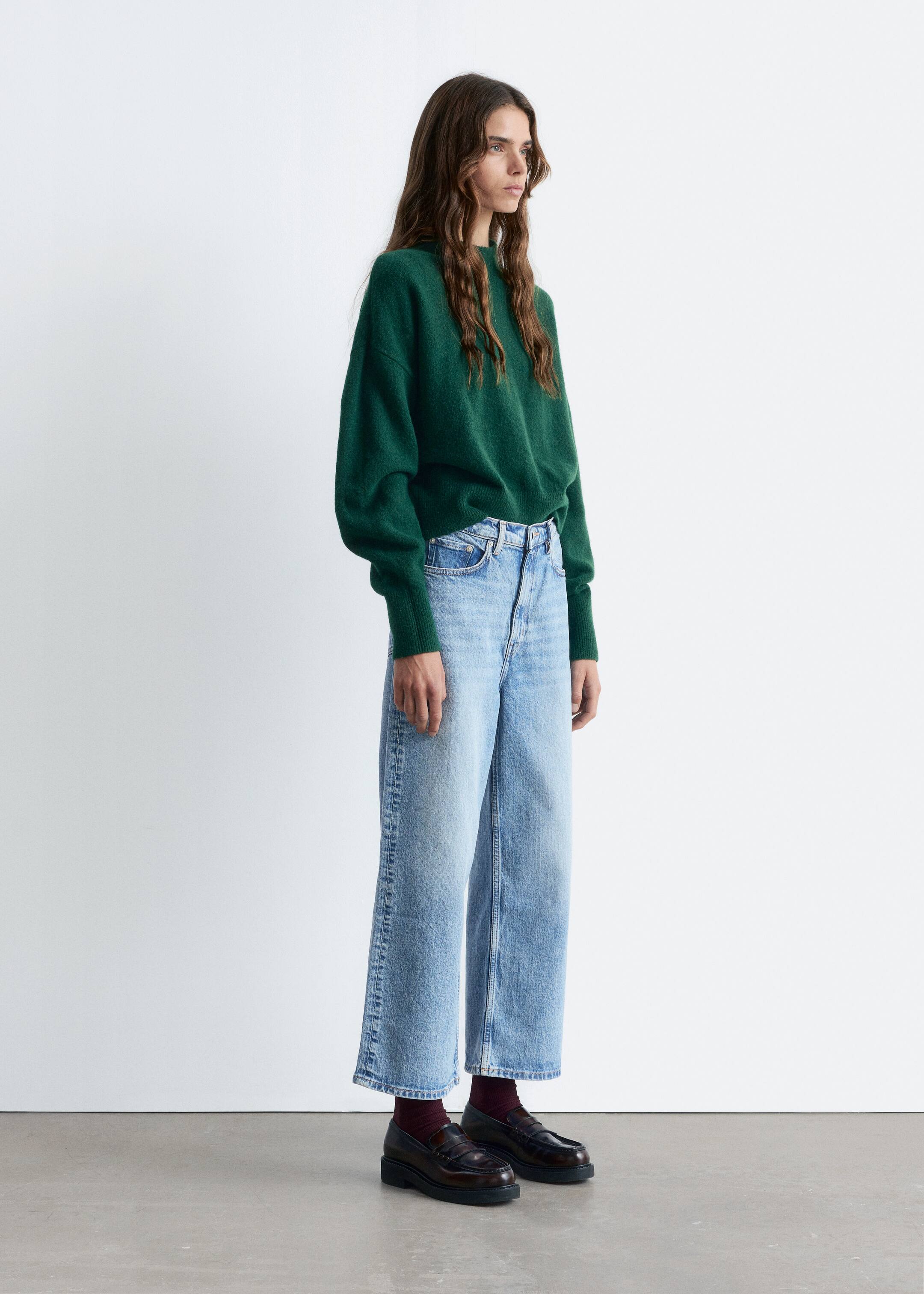 Visa större bild: En mörkgrön, avslappnad tröja med rund hals, med en mjuk textur och ribbade muddar, bärs och stylas med ljusa, högmidjade, vida och korta jeans som har en blekt finish. Mörka loafers med tjock sula och vinröda strumpor kompletterar utseendet.