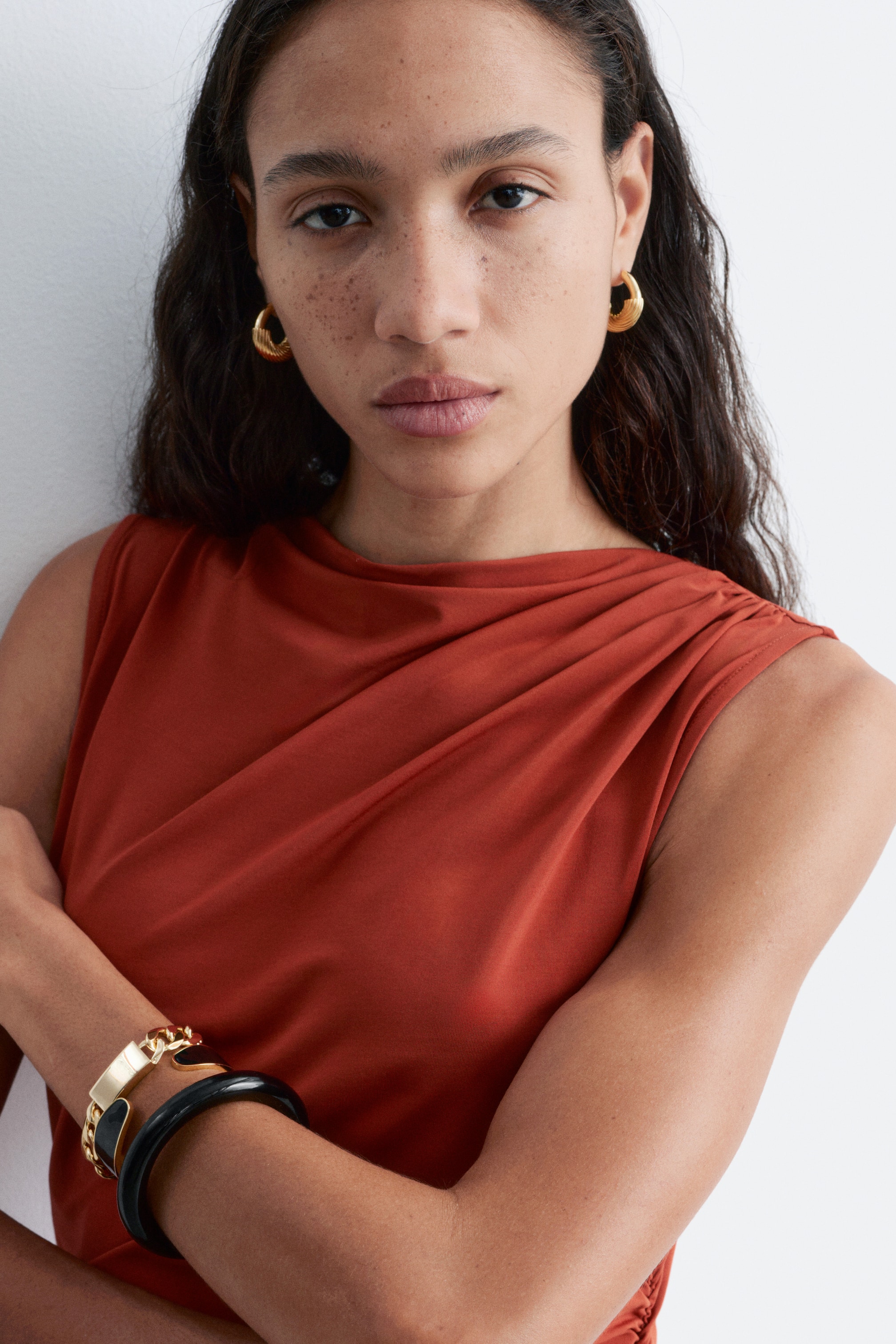 Agrandir l'image: Un haut sans manches de couleur rouille avec un décolleté drapé et des détails froncés sur l'épaule droite.