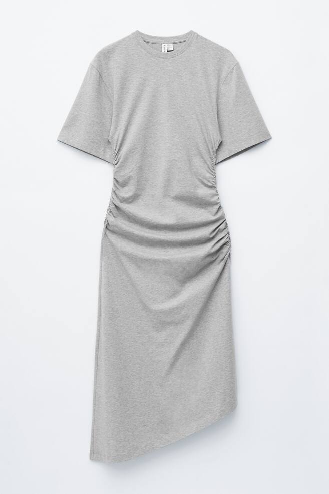 A light grey jersey T-shirt dress is presented FRONT, featuring a round neckline and short sleeves. Extensive ruching runs along both side seams, extending down to an asymmetrical hemline. - 1