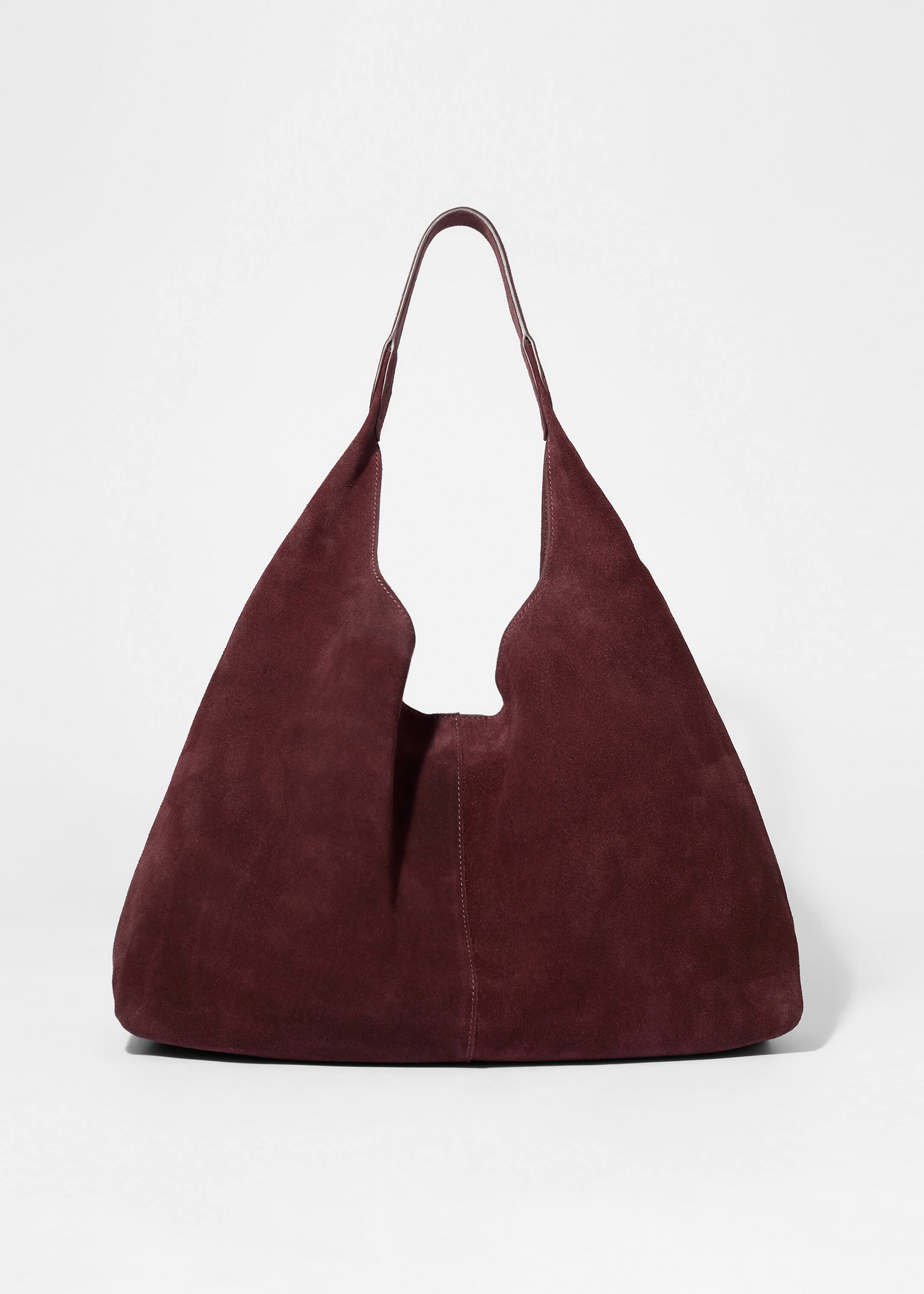 Agrandir l'image: Un sac fourre-tout d'un brun rougeâtre profond en daim lisse et mat présente son devant, avec une seule poignée et une couture décorative traversant le centre.