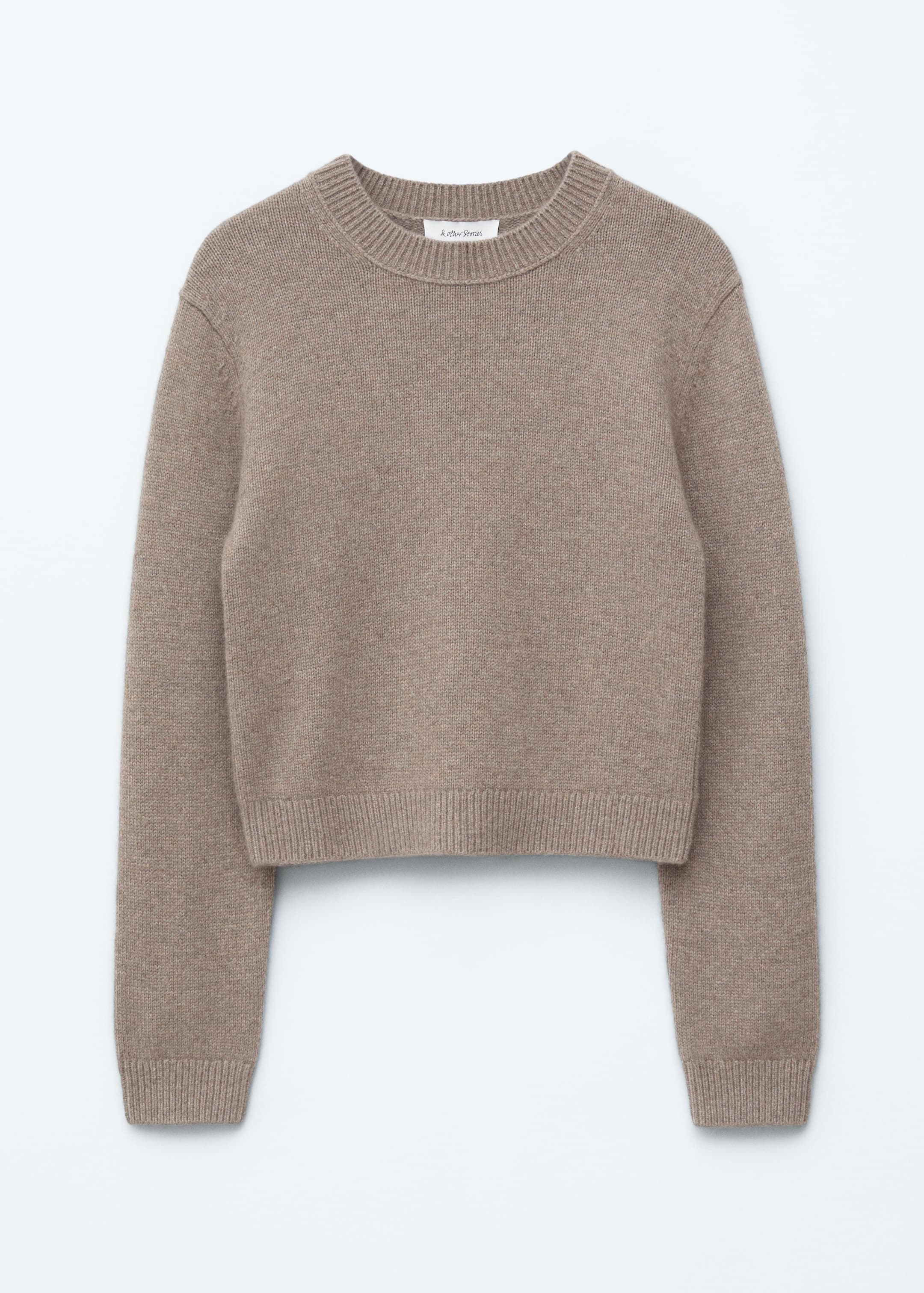 Agrandir l'image: Un pull court en tricot beige présente sa vue de face. Il est doté d'un col rond avec une bordure côtelée, des épaules légèrement tombantes, des manches longues avec des poignets côtelés et un ourlet côtelé.