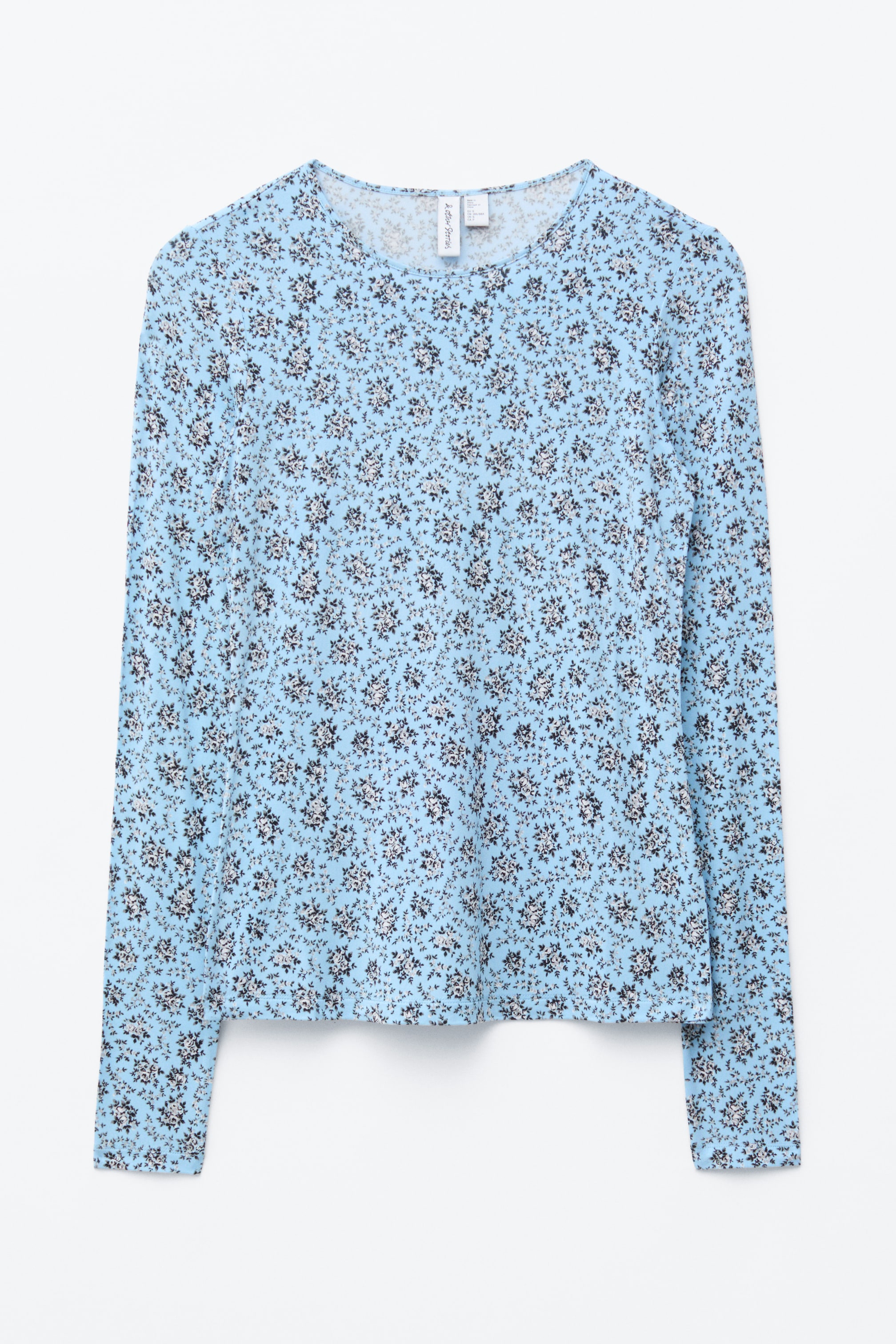 Zobrazit větší obrázek: Dlouhý rukáv je zobrazen naplocho, čelem dopředu, ukazující světle modrý základ s opakujícím se vzorem malých černobílých květinových motivů. Je střižen v rovném siluetě, s kulatým výstřihem, dlouhými rukávy a rovným lemem.