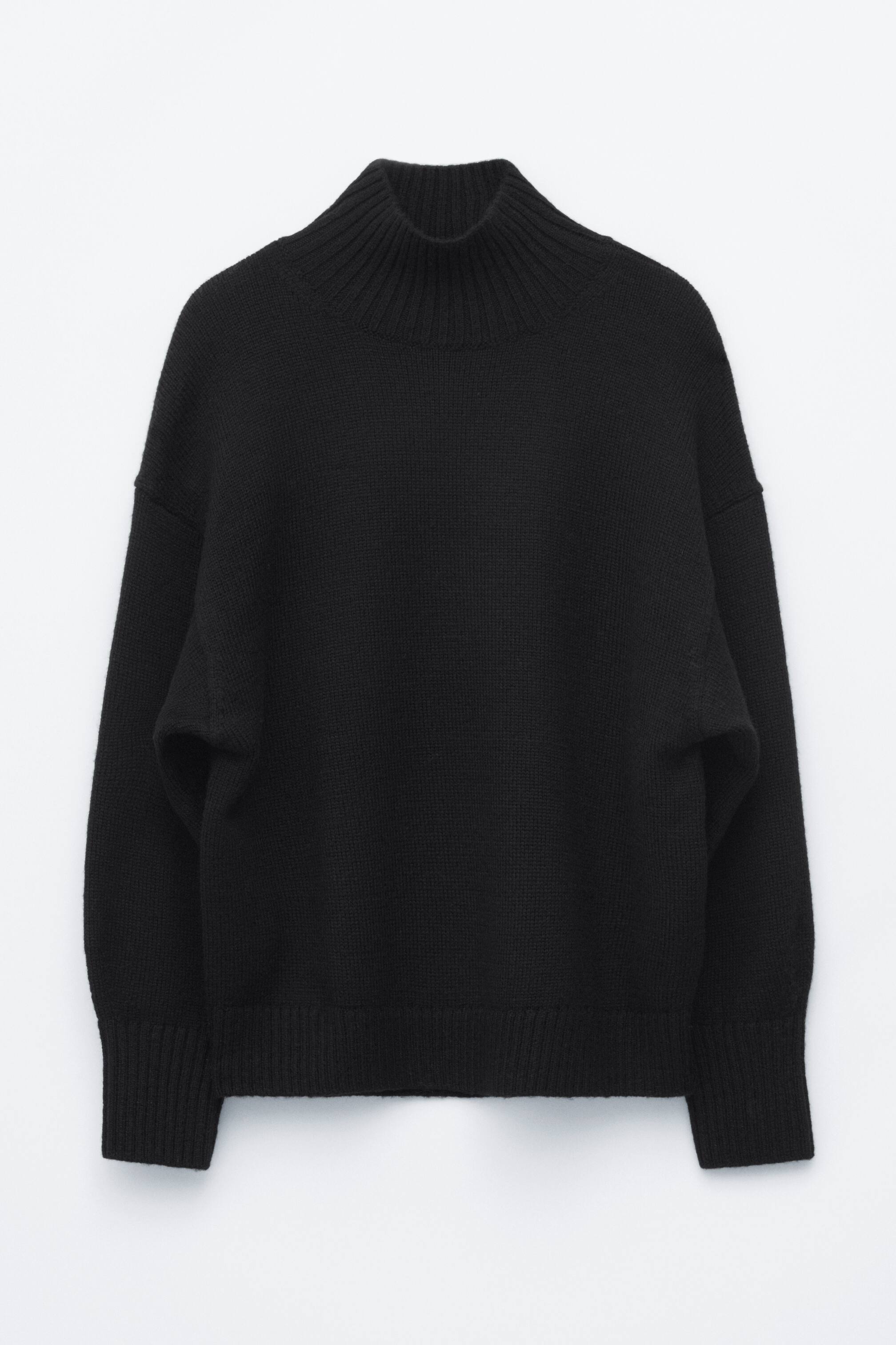 Vezi imaginea mai mare: Un pulover negru oversized din lână cu guler înalt este prezentat din față, evidențiind o siluetă relaxată, lejeră, cu umeri căzuți. Are un guler înalt ribat, mâneci lungi cu manșete late ribate și un tiv ribat asortat.