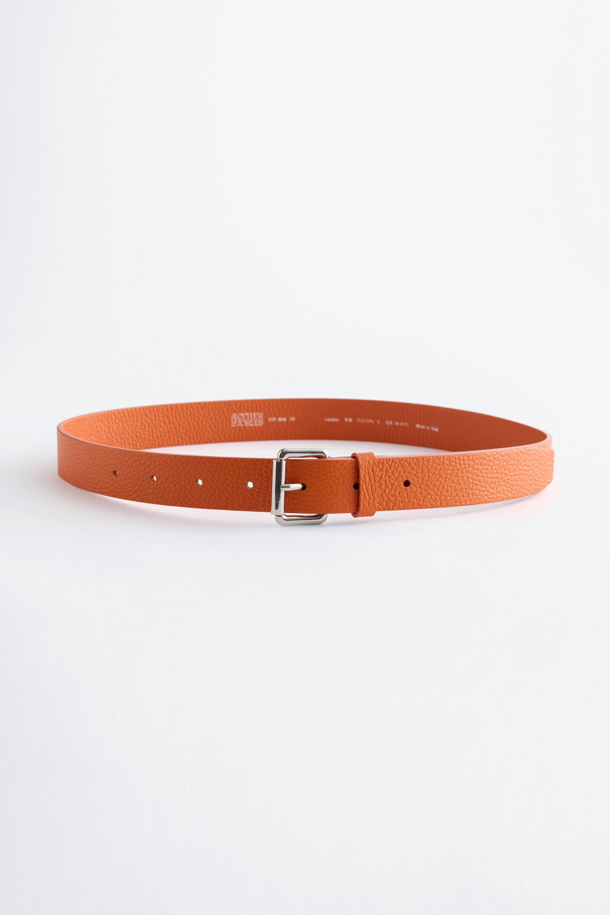 Ver imagem maior: Um cinto de couro laranja apresenta a sua textura granulada, furos de ajuste e uma fivela quadrada prateada com um único pino.