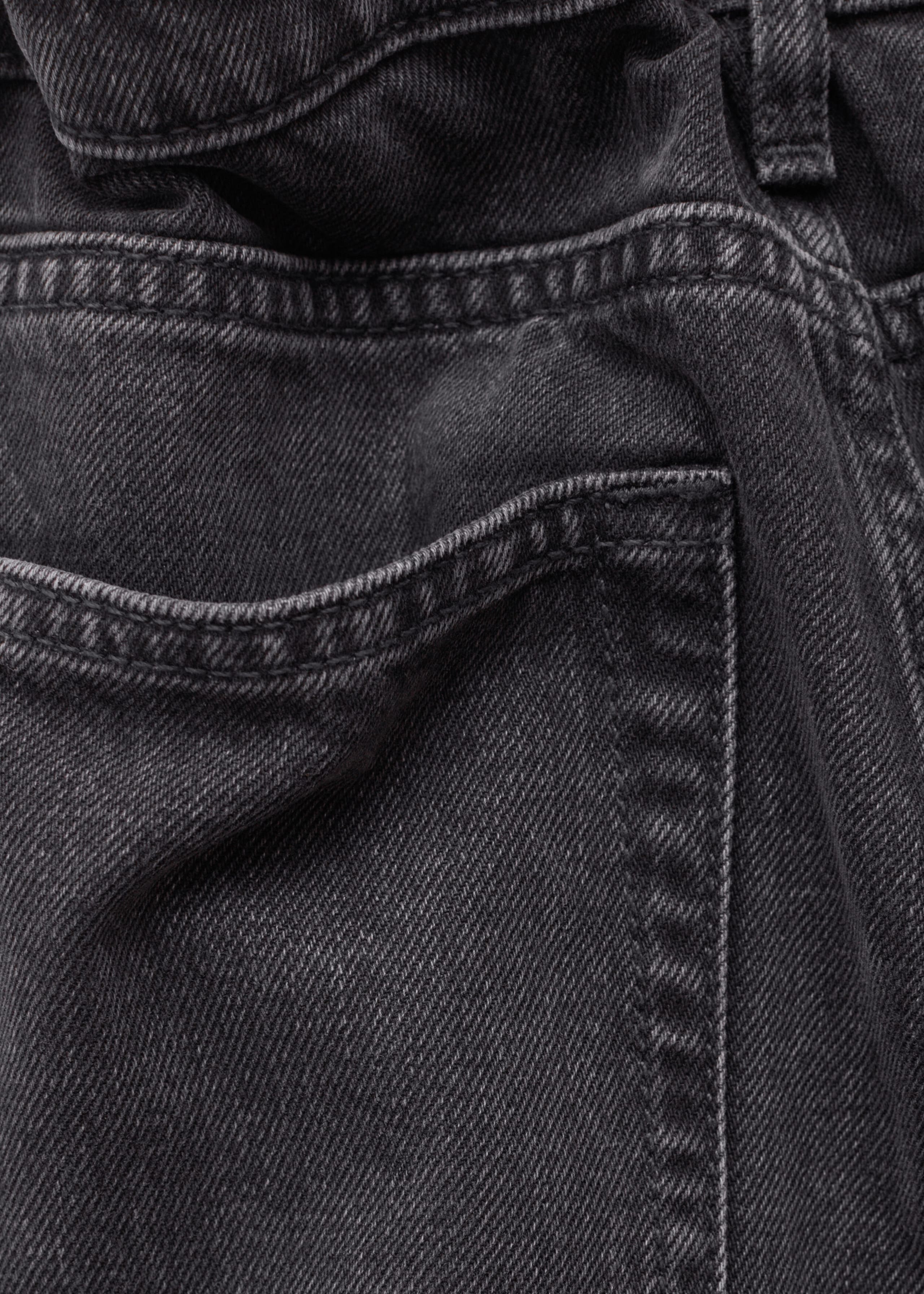 The dark gray denim jeans are shown in a close-up back view, highlighting the textured twill fabric, back pocket, waistband, and topstitching details.