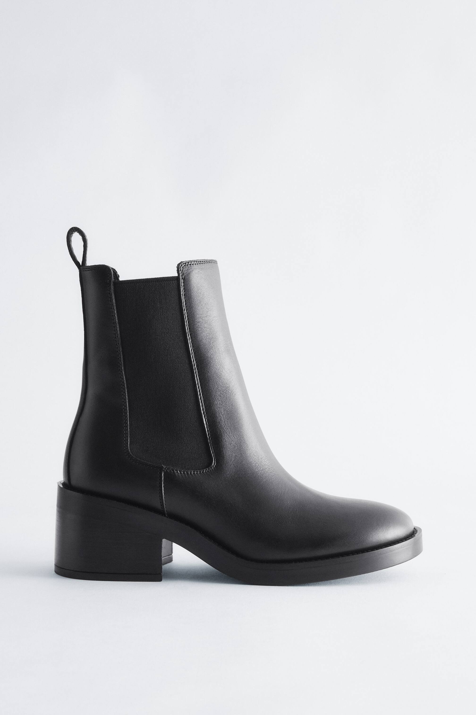 Grösseres Bild ansehen: Ein schwarzer Chelsea-Boot aus Leder steht in Seitenprofilansicht nach rechts gerichtet und zeigt sein glattes Lederobermaterial, das elastische Seitenelement, die hintere Anziehschlaufe und den kräftigen Blockabsatz.